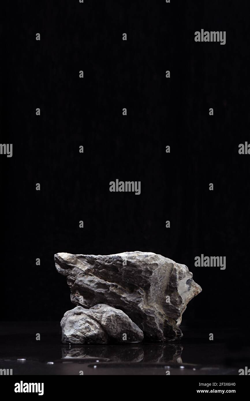 Elegante raue Naturstein Podium mit Wasser als Strand in der Nacht für die Darstellung von Verpackung und Produkt auf schwarzem Hintergrund. Stockfoto