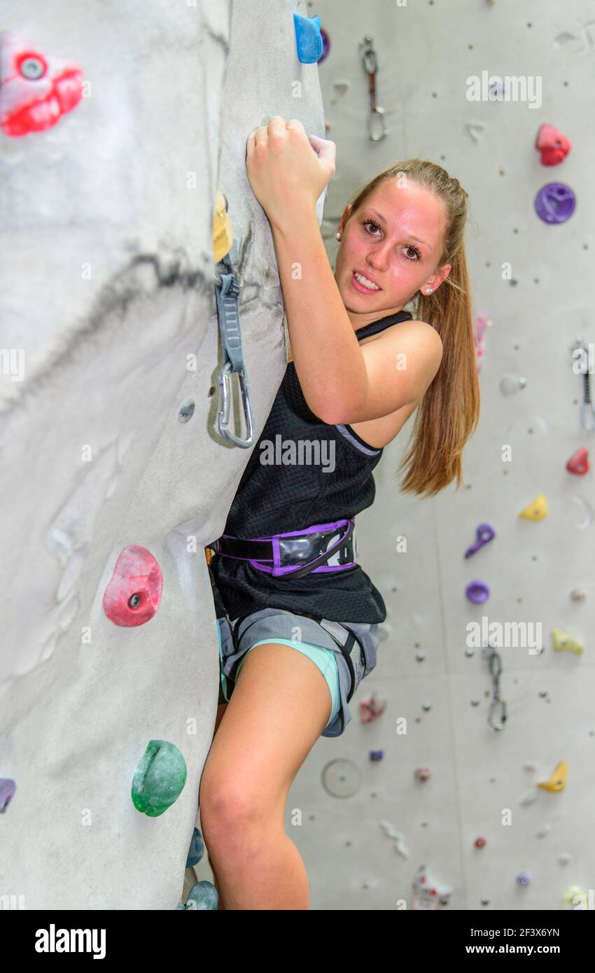 Weibliche Kletterer während ihrer anstrengenden Workout an einer Wand in die Kletterhalle Stockfoto