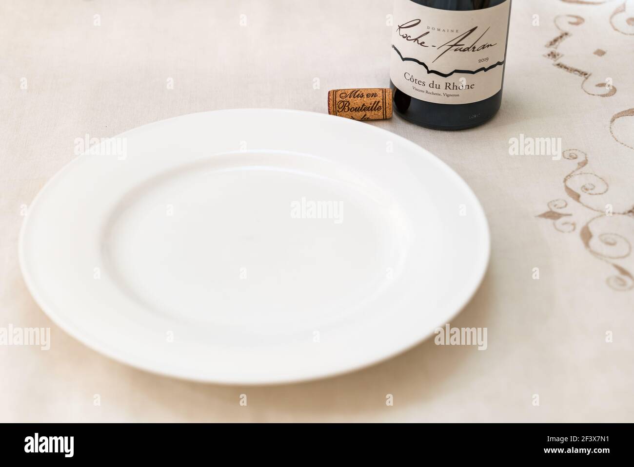 Weißer leerer Teller mit Flasche Cote du Rhone Roche Audran Französischer Rotwein und Weinkorken Stockfoto