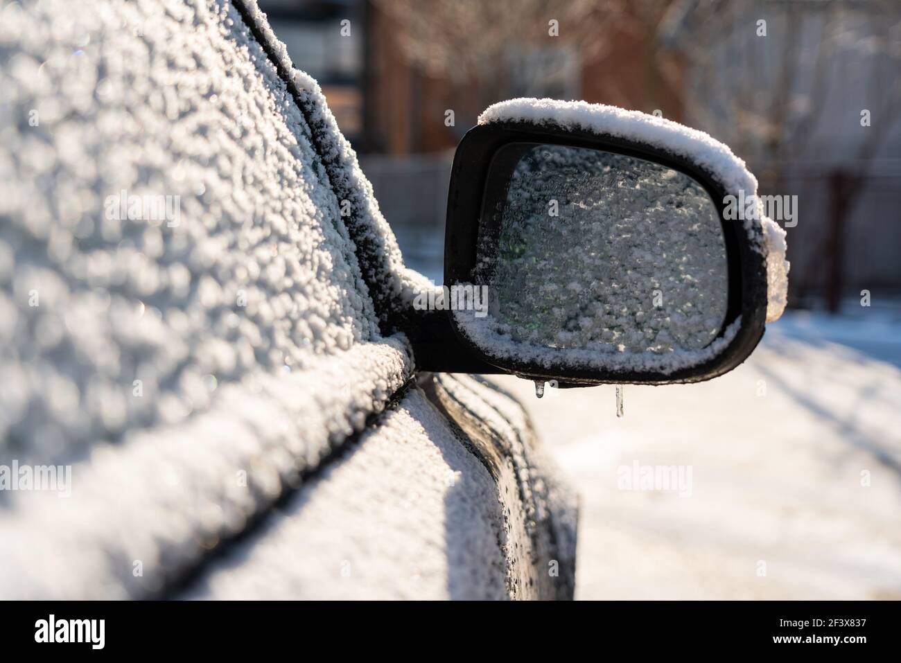 Auto mit Eis und Eiszapfen nach Glatteisregen bedeckt. Eisbedecktes Autofenster aus der Nähe. Schlechtes Winterwetter, EissturmWinter frostige Szenen. Stockfoto