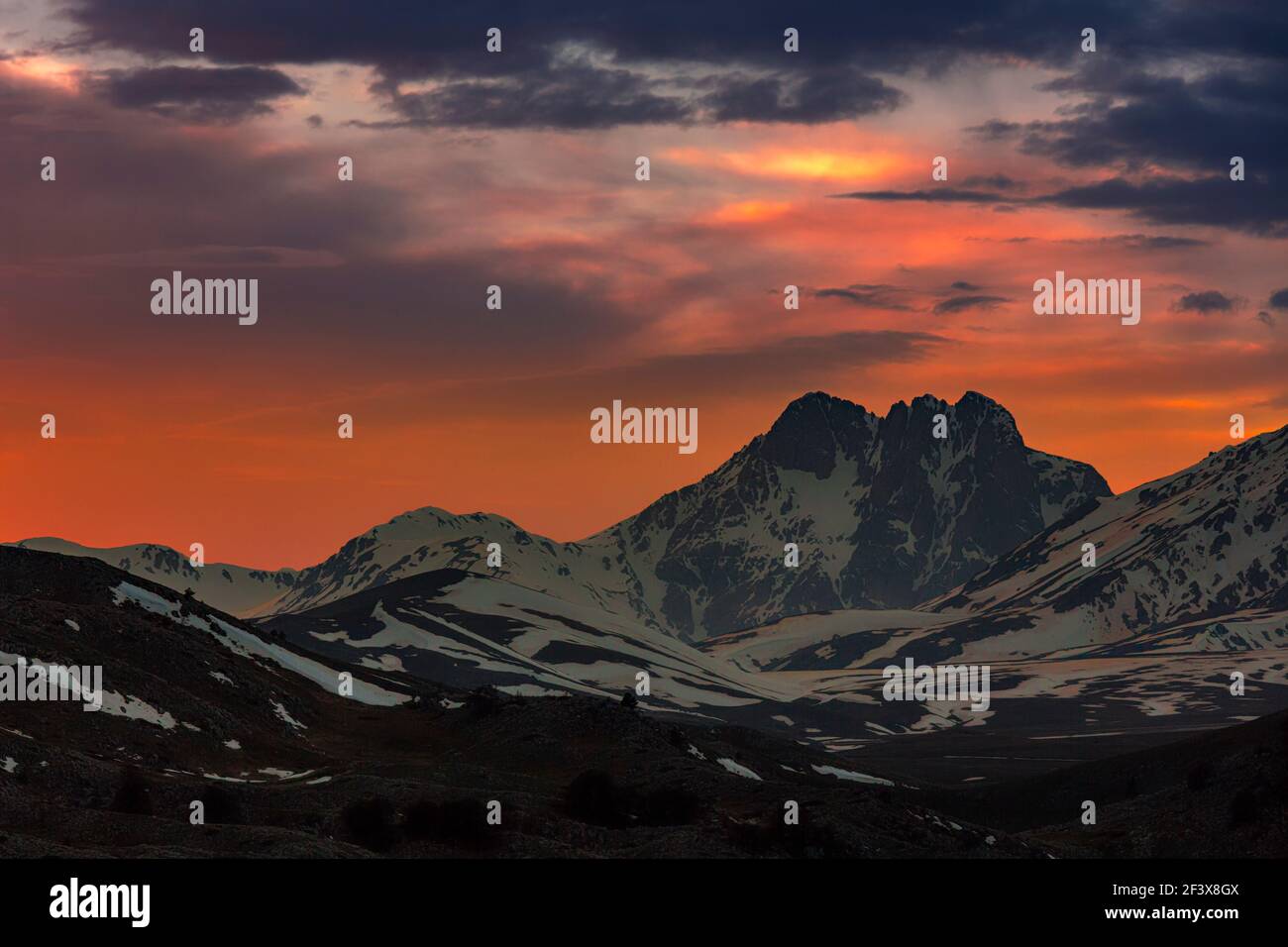 Feuriger und roter Sonnenuntergang auf dem schneebedeckten Corno Grande. Gran Sasso und Nationalpark Monti della Laga. Abruzzen Stockfoto