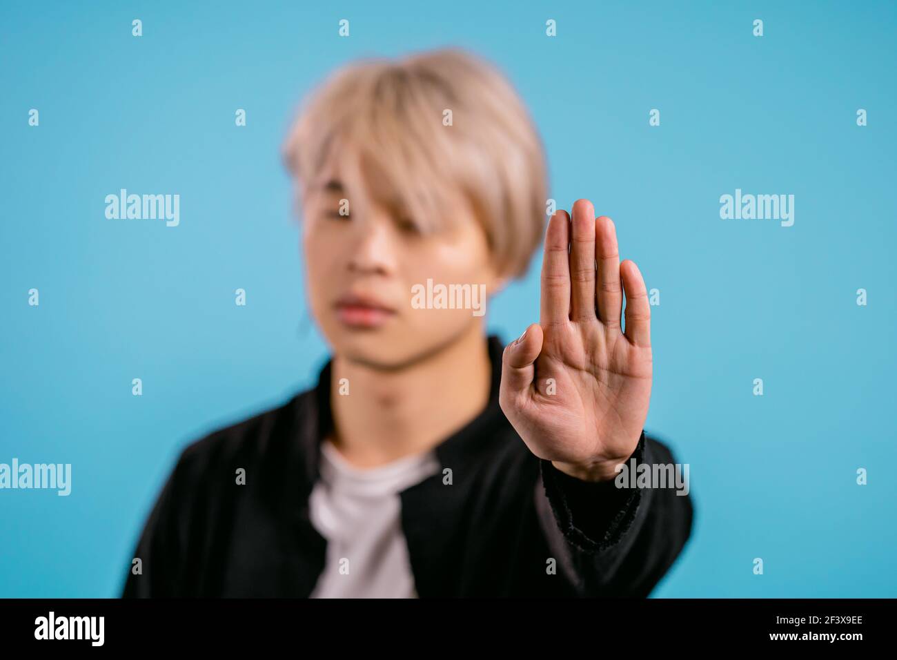 Asiatischer Mann missbilligt ohne Handzeichen Geste. Leugnen, Ablehnung, nicht einverstanden, Porträt von schönen koreanischen Kerl oder Student auf blauem Hintergrund Stockfoto