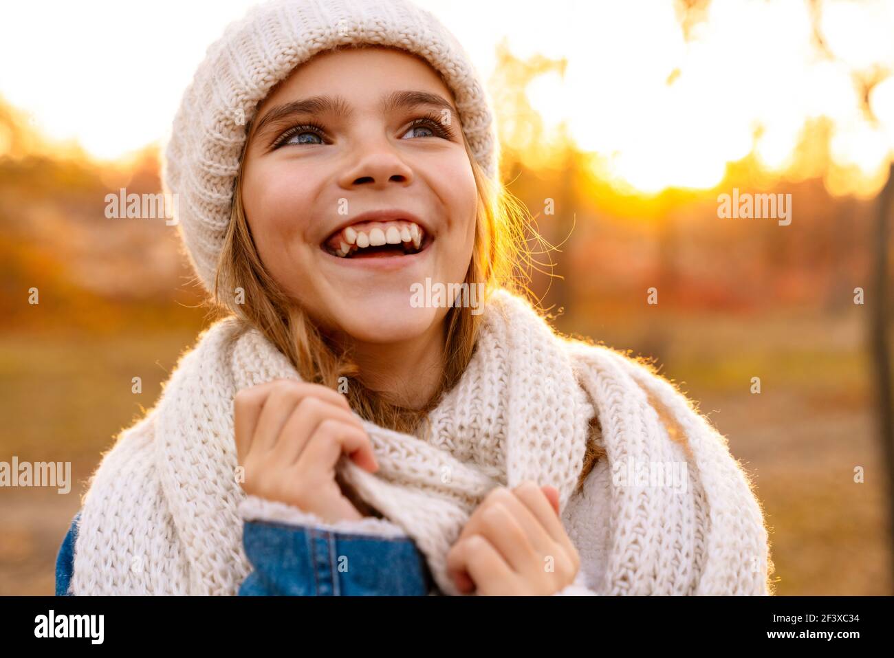 Lächelndes Mädchen in gestrickten Hut und Schal zu Fuß in der Herbstpark Stockfoto