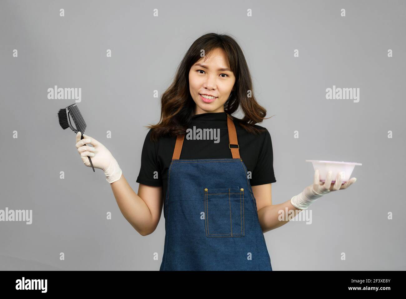 Portrait von Asian wunderschöne fröhlich junge weibliche professionelle Friseur Holding Applizierten Haarfarbe mit einem Pinsel lächeln auf die Kamera Posiert sie an Stockfoto