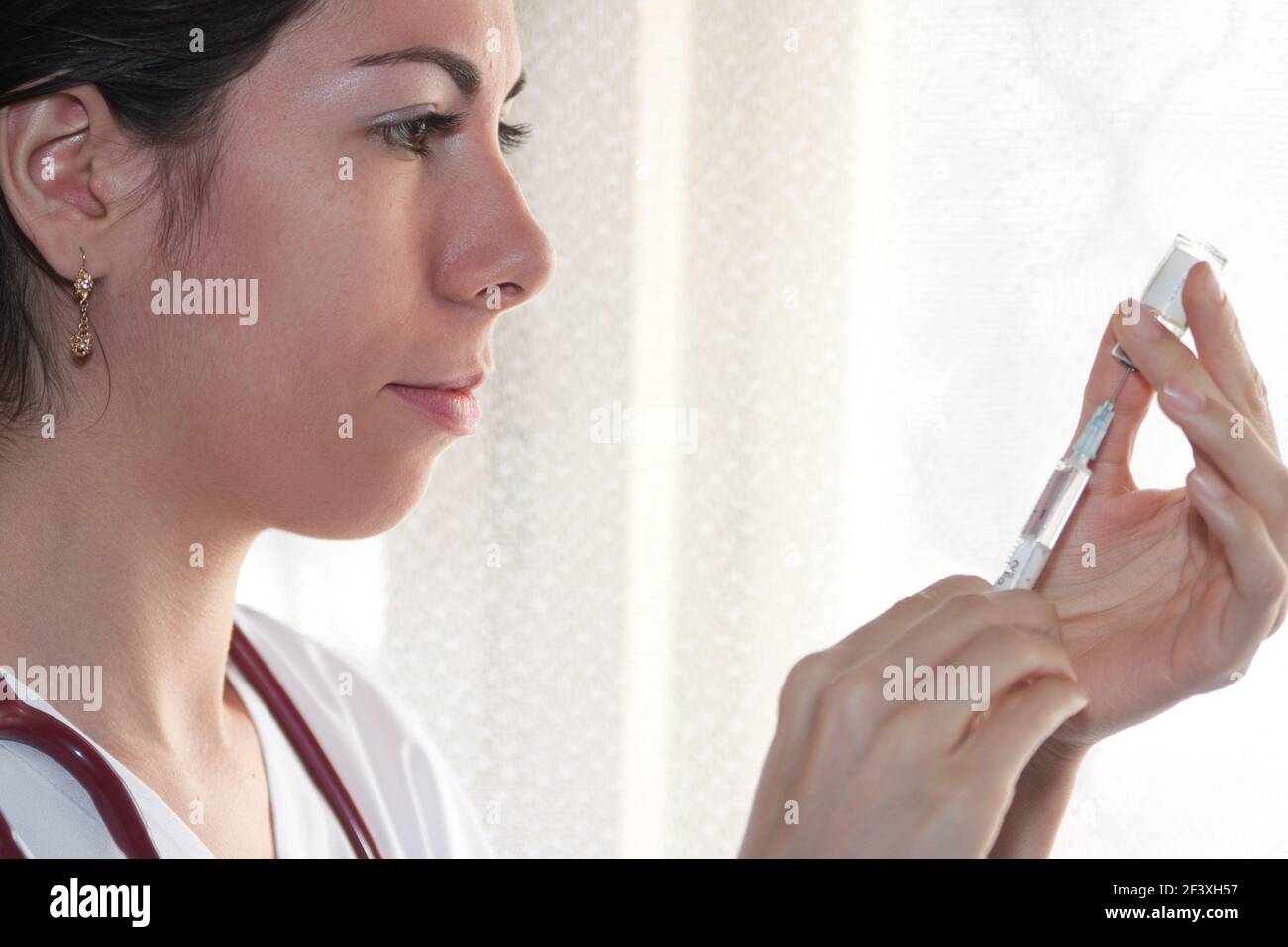 Ärztin bereitet einen Covid 19-Schuss vor, indem sie das Serum mit einer Spritze aus der Impfampulle extrahiert. Stockfoto