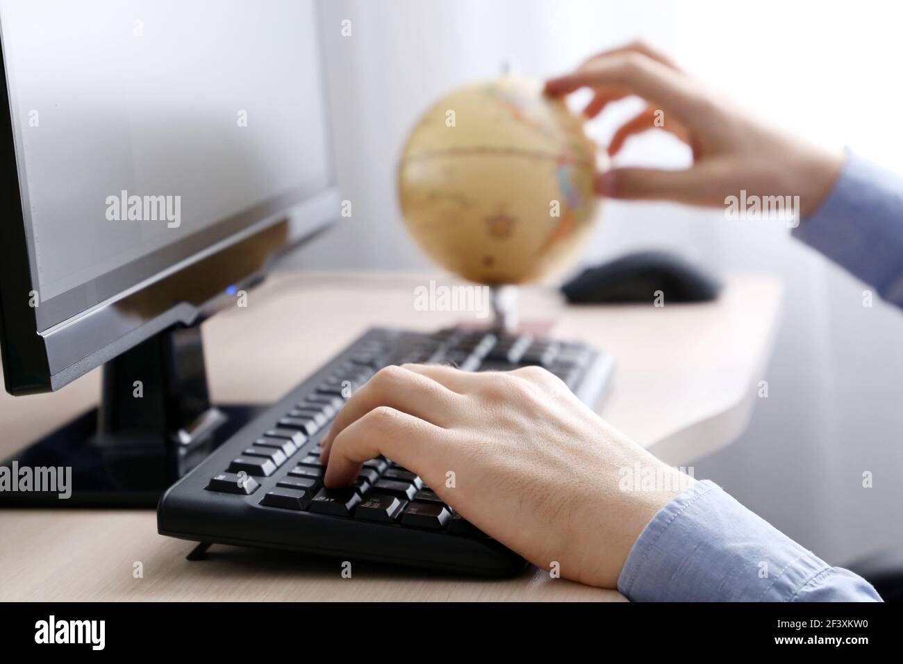 Mann mit Globus sitzt an der PC-Tastatur. Konzept der Wahl Reise Tour Stockfoto