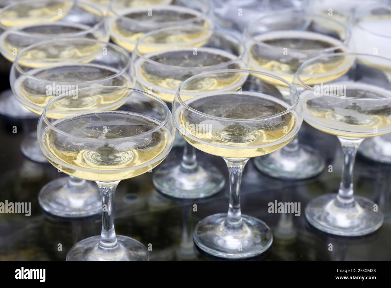 Gläser mit weißem Sekt, Champagner spiegeln sich in Glastisch. Konzept der Feier, Abendgesellschaft, Empfang Stockfoto