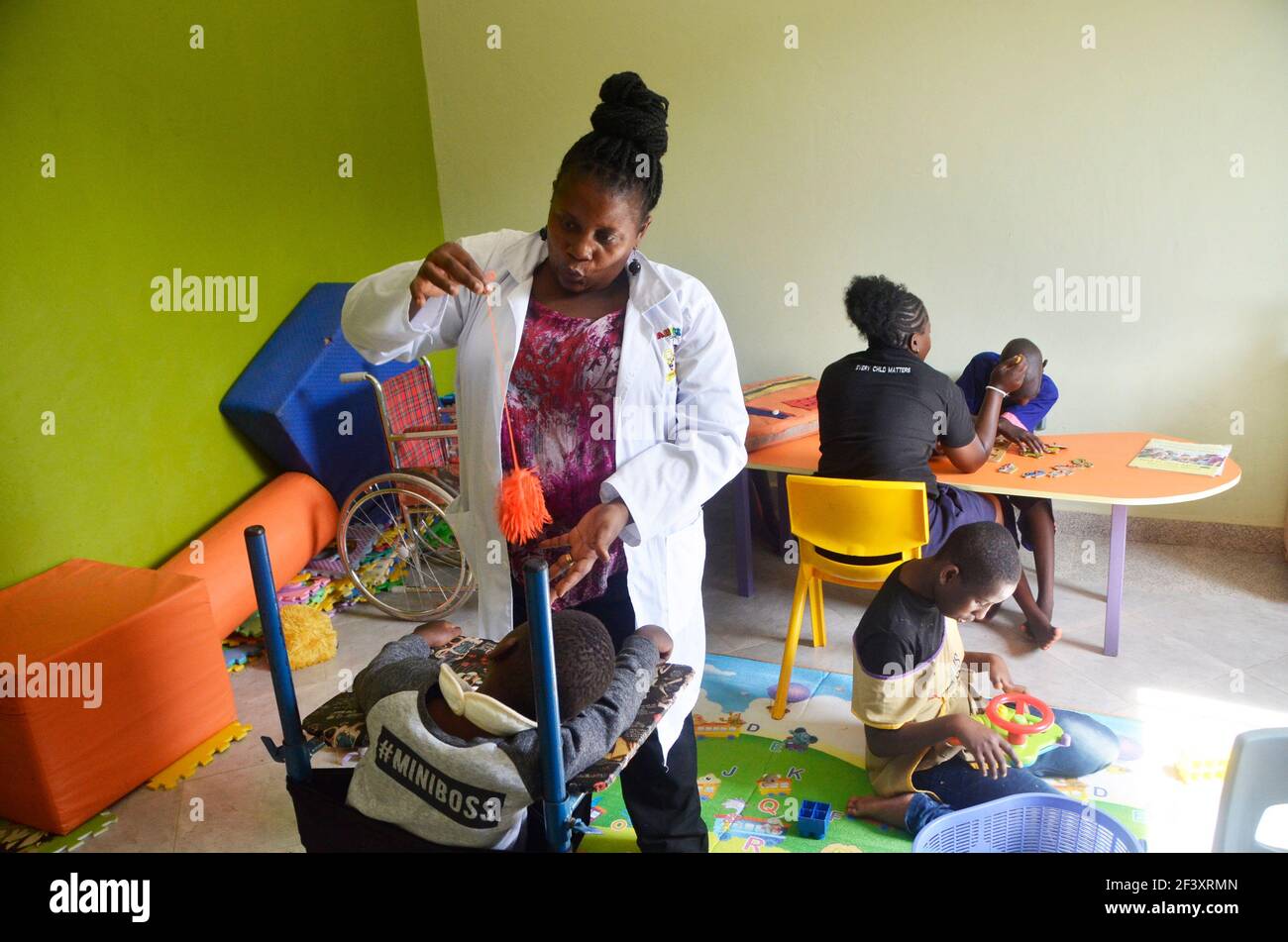 Wakiso, Uganda. März 2021, 17th. Eine Frau spielt mit Kindern im Angel's Centre im Wakiso Distrikt, Zentral-Uganda, 17. März 2021. Angel's Center wurde von Rose Nambooze, der Mutter eines Kindes mit Down-Syndrom gegründet. Die Mitarbeiter des Zentrums kümmern sich um 100 Kinder mit Down-Syndrom, Zerebralparese, Hydrocephalus und Autismus. Quelle: Nicholas Kajoba/Xinhua/Alamy Live News Stockfoto