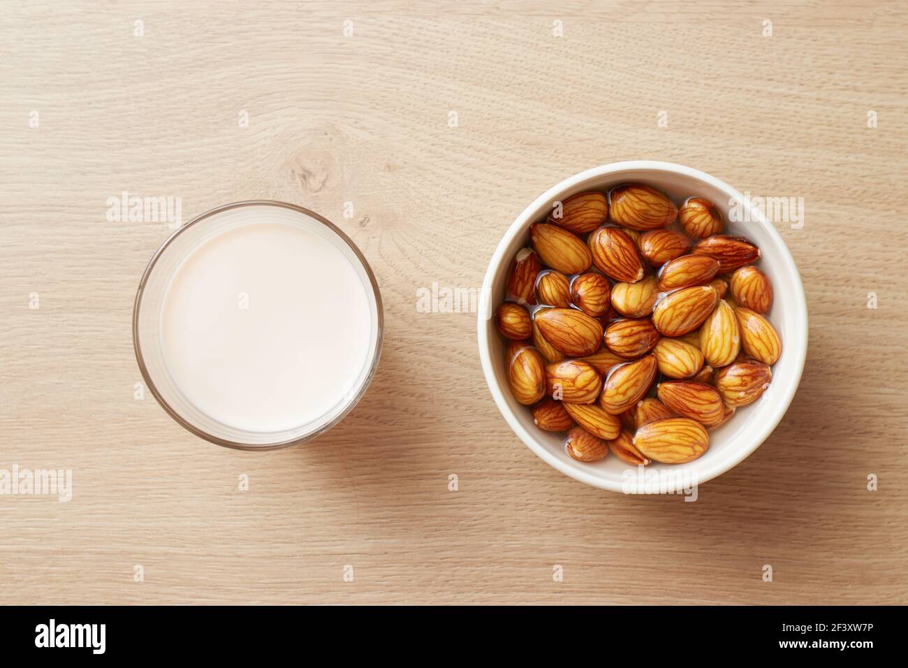 Ein Glas hausgemachter veganer Mandelmilch und mit Wasser getränkte Mandeln Stockfoto