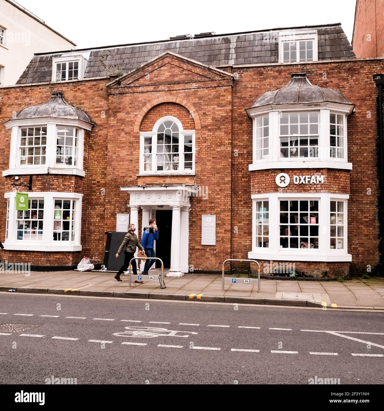 London, Großbritannien, März 18 2021, Mann und Frau Familienpaar beim Spaziergang an einem Oxfam Charity Shop vorbei Stockfoto