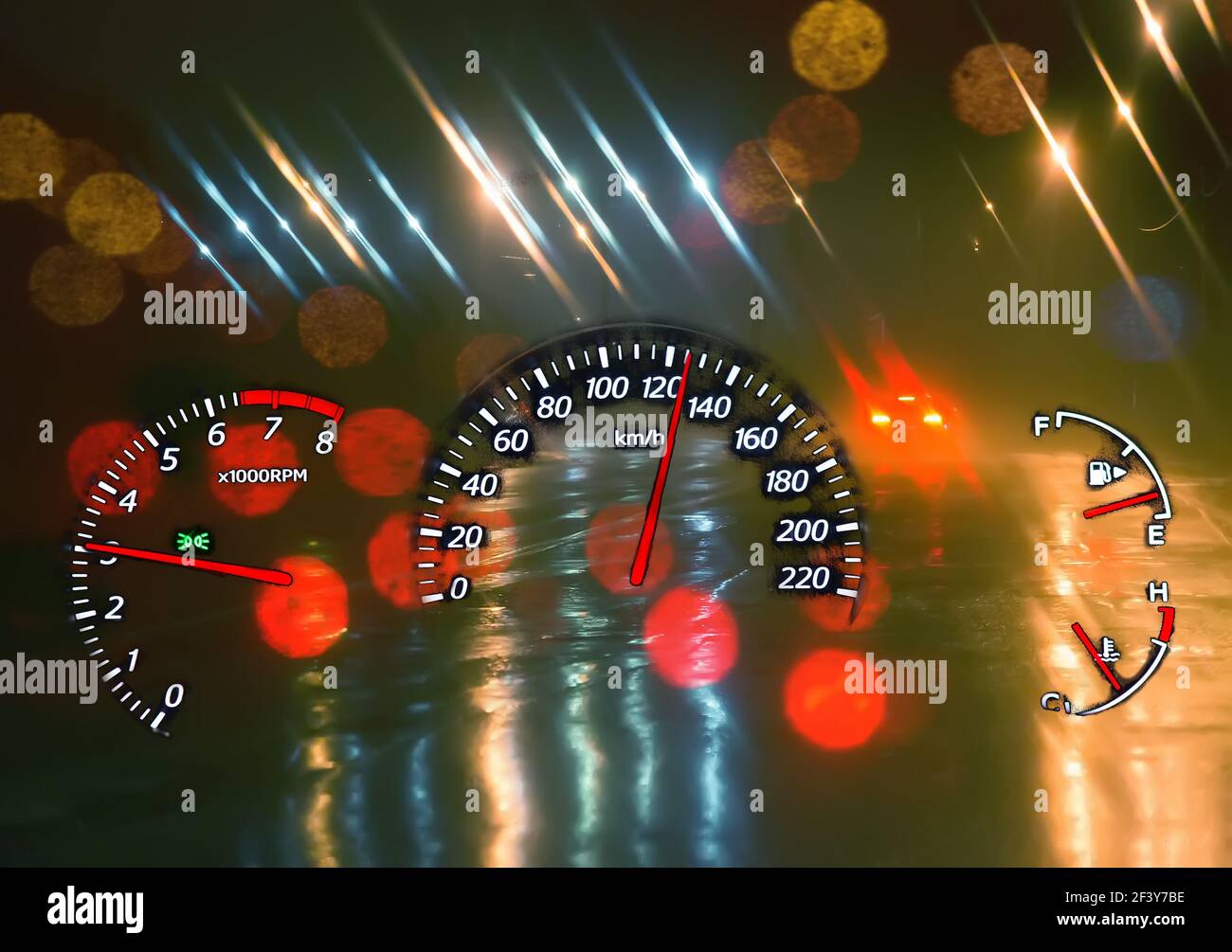 Tachometer und ein Tachometer auf einem Hintergrund einer nächtlichen nassen Straße. Überdrehzahl. Gefährliches Fahren. Stockfoto