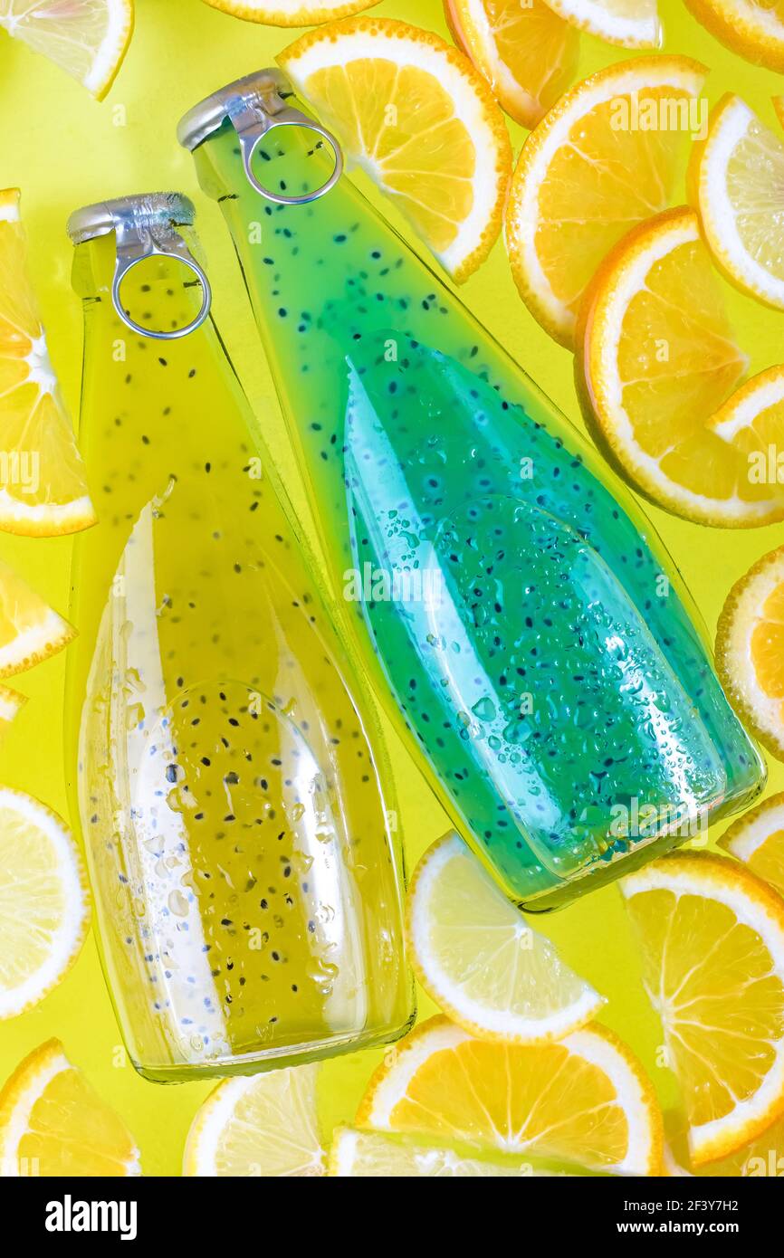 Blaue und gelbe Getränke mit Samen in Glasflaschen auf tropischem Hintergrund aus Scheibe Orange, Zitrone Smoothie. Kaltes Getränk in Wasser. Sommer le Stockfoto