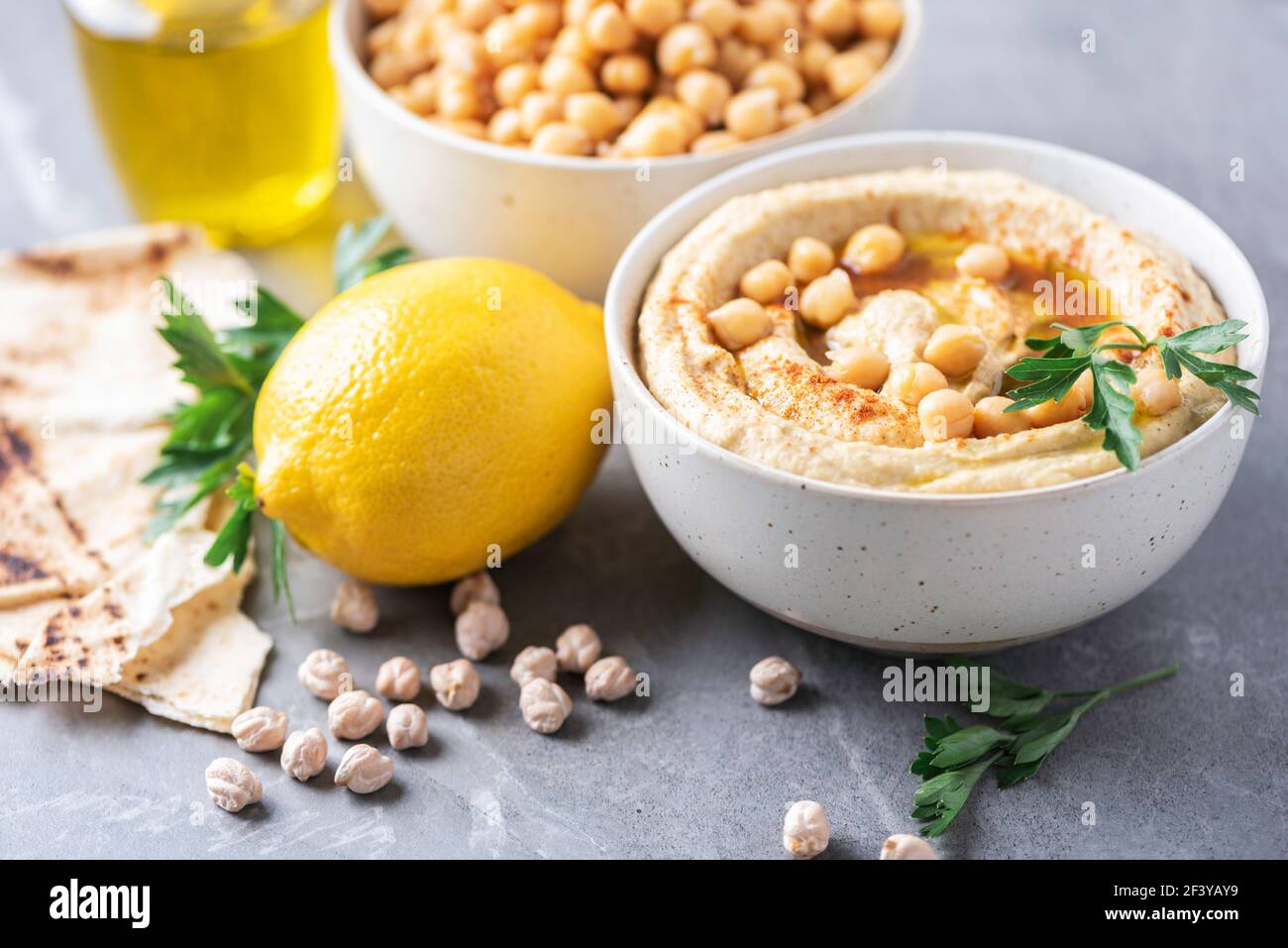 Hummus, Kichererbsen-Dip, Olivenöl, rohe Bohnen, geräucherter Paprika, Pita auf grauem authentischem Hintergrund. Nahöstliche, jüdische Küche oder arabische Gerichte. Makro Stockfoto