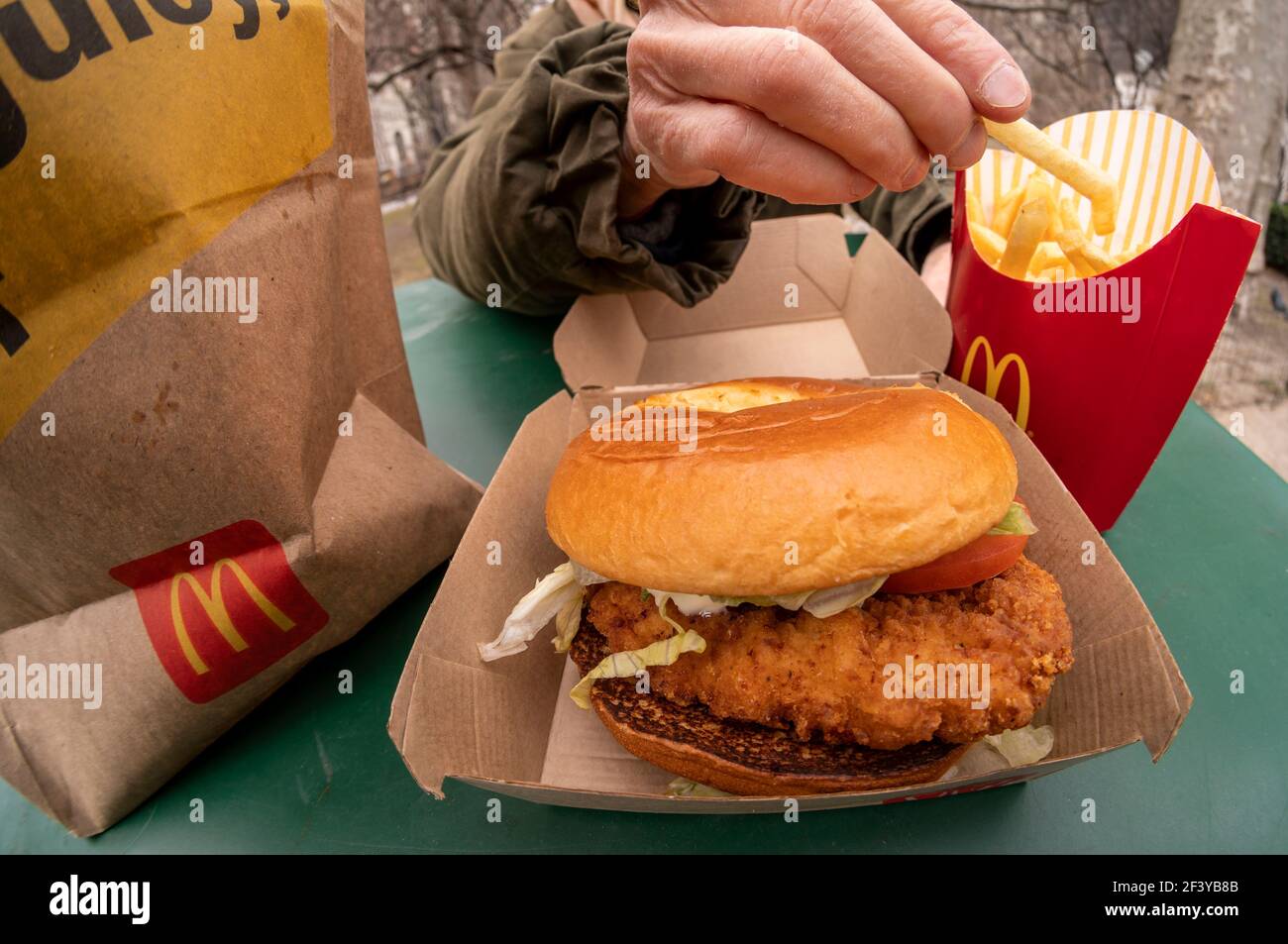 New York, USA. März 2021, 17th. Ein Diner bereitet das Mittagessen auf einem McDonald's Crispy Chicken Sandwich Deluxe zu, während er am Mittwoch, 17. März 2021, im Freien in New York zu Abend gegessen hat. Im Jahr 2019 Popeye's debütierte seine Huhn-Sandwich zu großem Erfolg führt fast jede Fast-Food-Kette zu einem knusprigen Huhn Menüelement zu generieren. McDonald's ist schließlich als 800-Pfund-Gorilla eingestiegen und hat bereits zu einer Steigerung des Fußgängerverkehrs in seinen Restaurants geführt. (ÂPhoto von Richard B. Levine) Quelle: SIPA USA/Alamy Live News Stockfoto