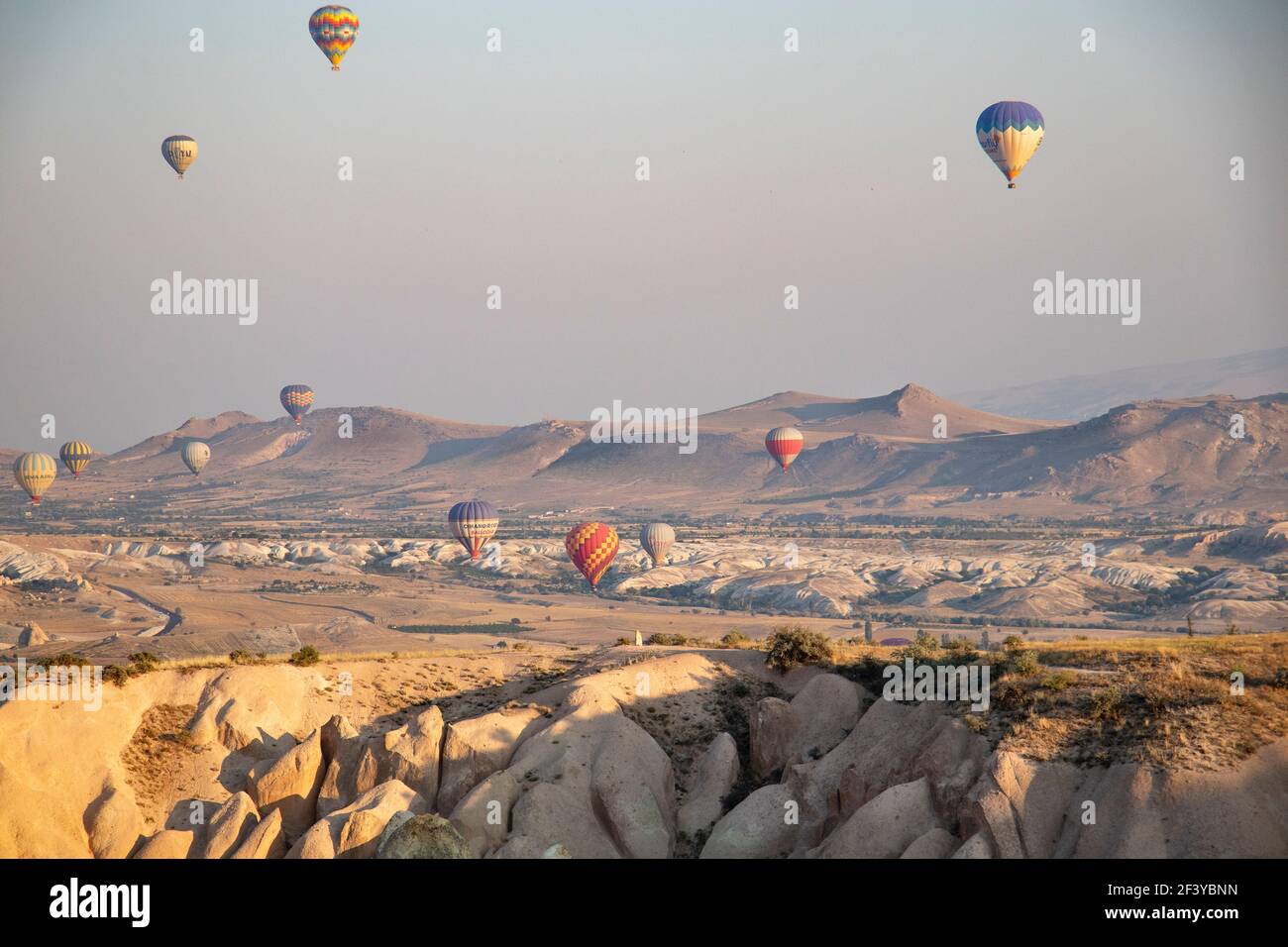 Türkei, Kappadokien, Goreme, 1. August 2019. Bunte Luftballons am Himmel über sandigen Bergen Stockfoto