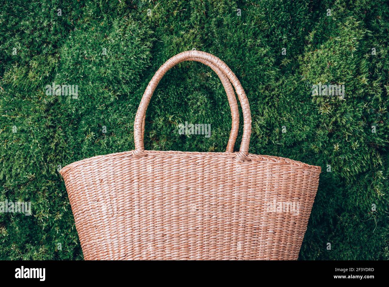 Stroh Netzbeutel auf grünem Gras Moos Hintergrund. Sommerpicknick im Wald. Draufsicht. Speicherplatz kopieren. Erholung im Freien. Digitale Entgiftung. Ziehen Sie Den Stecker Ab Stockfoto