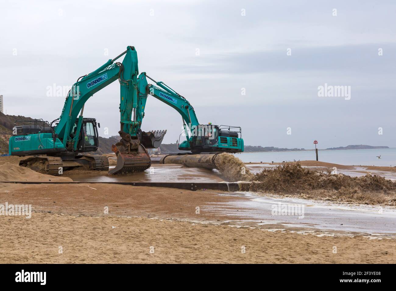Bournemouth, Dorset, Großbritannien. März 2021, 18th. Am Strand von Bournemouth wird der Sand von einem Bagger durch Rohre aus dem Meer auf die Strandküste gepumpt. Mit mehr Menschen wahrscheinlich zu bleiben in diesem Jahr und Urlaub in Bournemouth die goldenen Sandstrände sind Teil der Attraktion. Ovenden SK500 Bagger - Wasser und Sand werden ausgepumpt und sprudeln. Quelle: Carolyn Jenkins/Alamy Live News Stockfoto