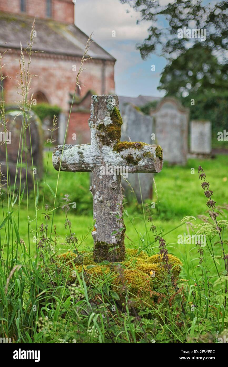 Altes hölzernes Kreuz, das mit Moos auf einem Friedhof bedeckt ist England Stockfoto