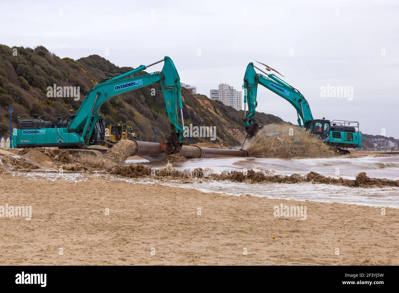Bournemouth, Dorset, Großbritannien. 18th. März 2021. Am Strand von Bournemouth wird der Sand von einem Bagger durch Rohre aus dem Meer auf die Strandküste gepumpt. Mit mehr Menschen wahrscheinlich zu bleiben in diesem Jahr und Urlaub in Bournemouth die goldenen Sandstrände sind Teil der Attraktion. Ovenden SK500 Bagger - Wasser und Sand werden ausgepumpt und sprudeln. Quelle: Carolyn Jenkins/Alamy Live News Stockfoto