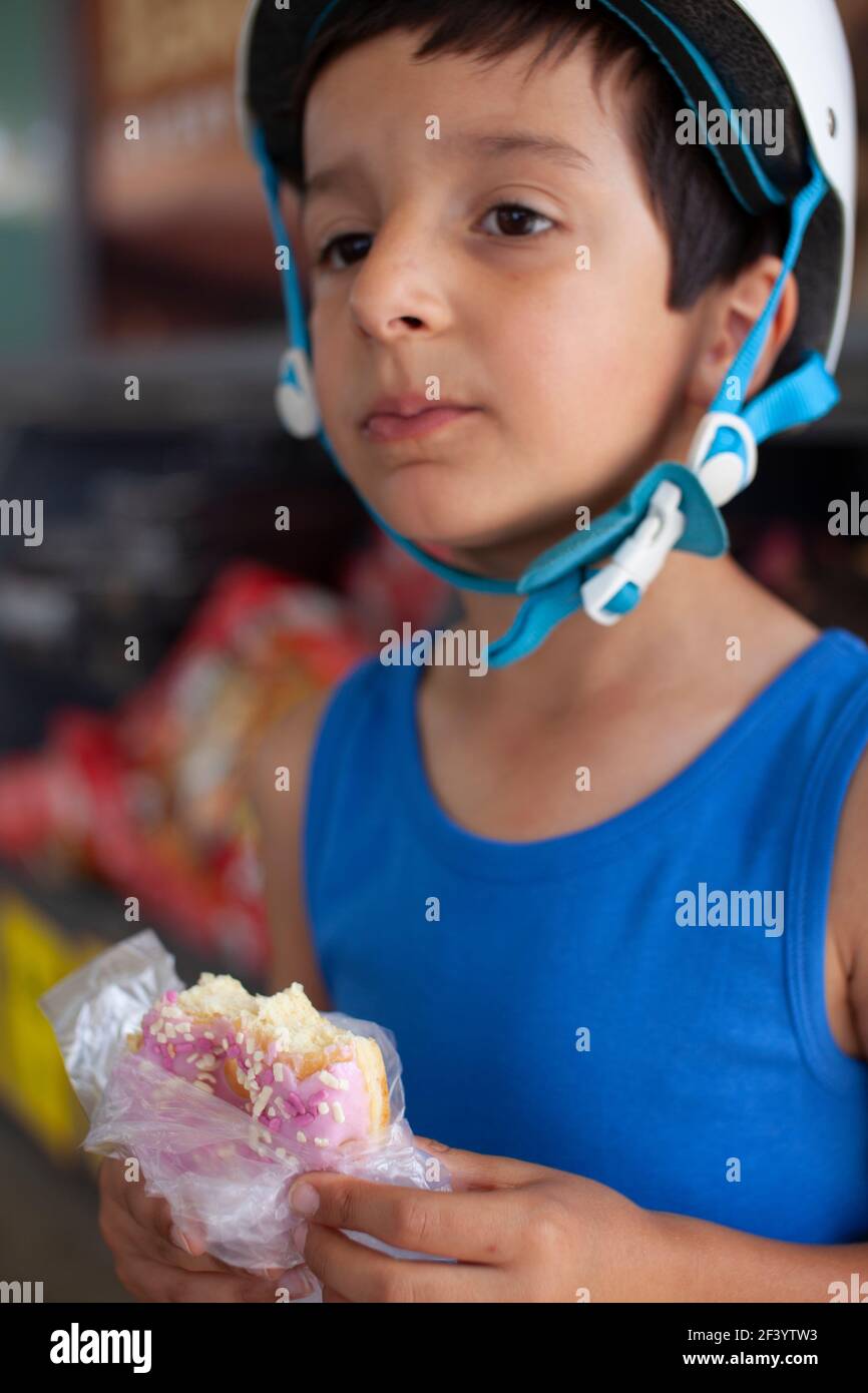 Kleiner Junge, 6 Jahre alt, der mit Zucker beschichteten Donut isst Stockfoto