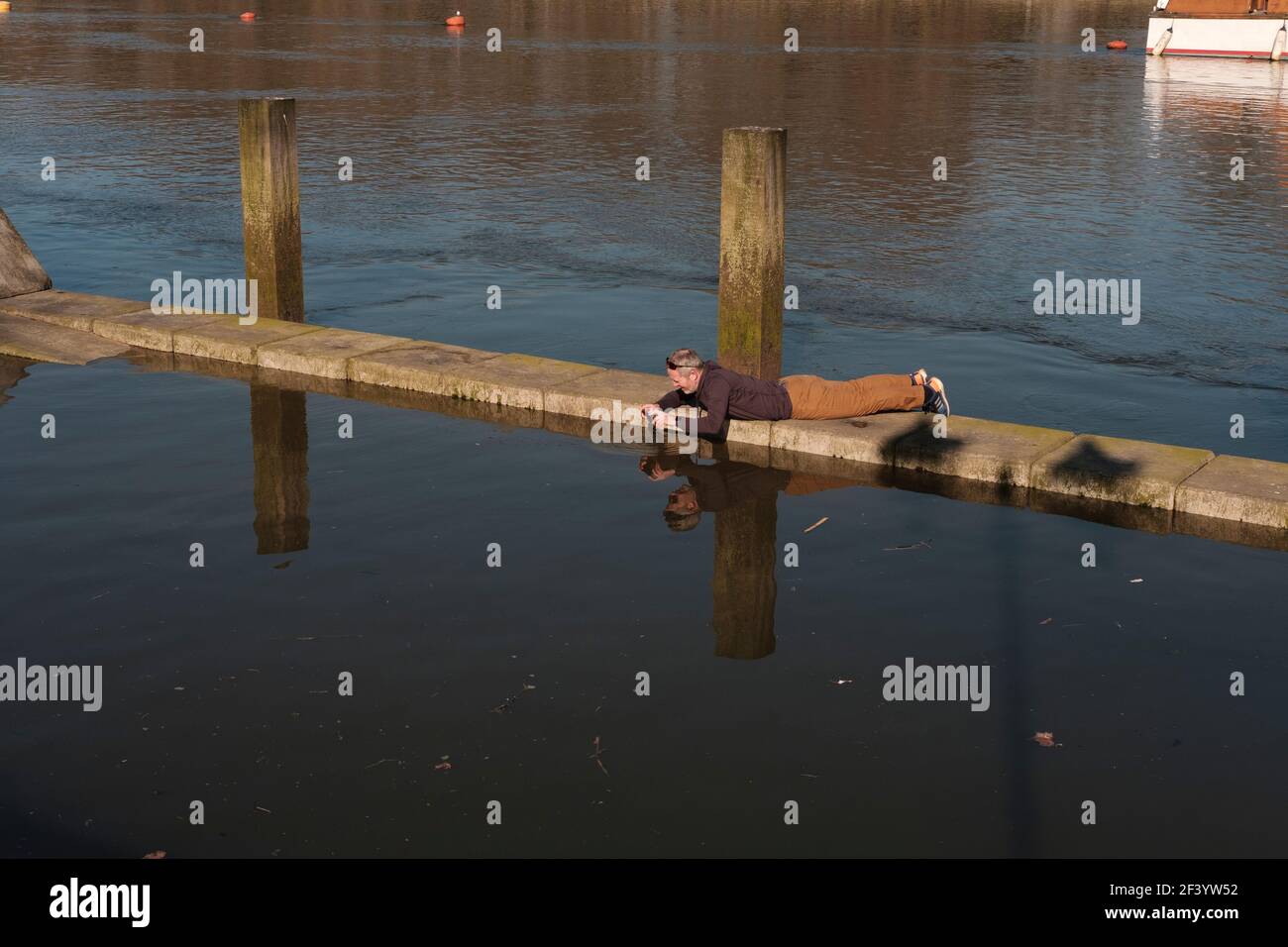 Mann mittleren Alters, der mit ihm Bilder von der Themse machte Wasserdichtes Mobiltelefon, Putney, London, England Stockfoto