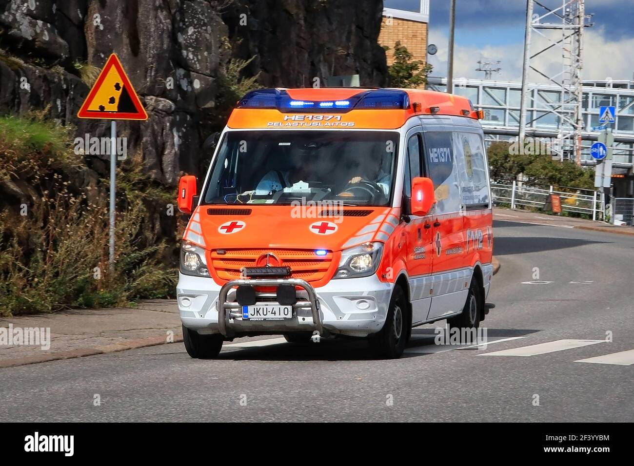 Rettungswagen auf Notruf Beschleunigung entlang der Straße während des Tages. Detail: Falling Rocks Verkehrsschild. Helsinki, Finnland. August 24 20. Stockfoto