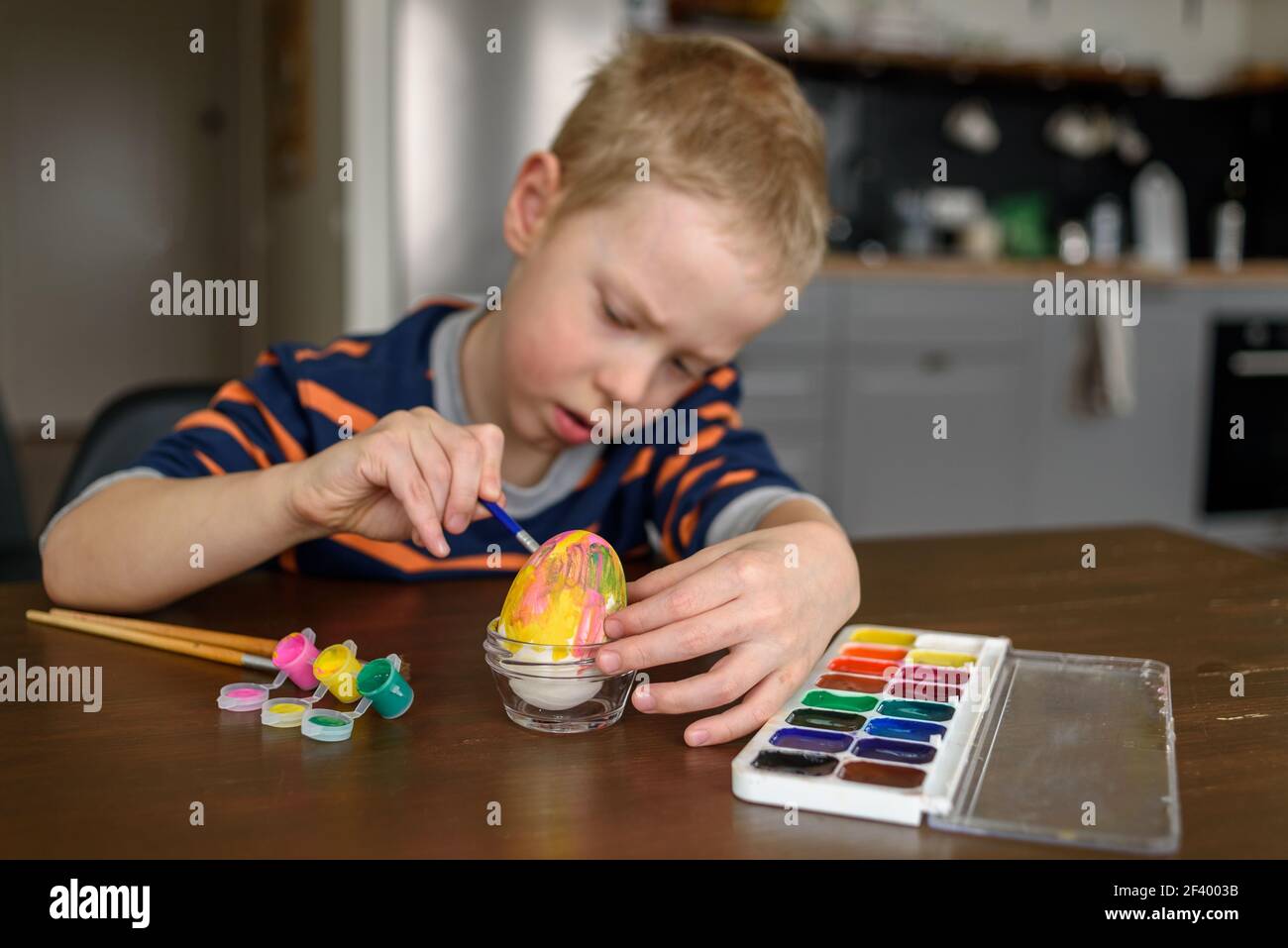 Junge Färbung Osterei zu Hause mit Acrylfarbe. Kleiner Künstler, Hobby Stockfoto