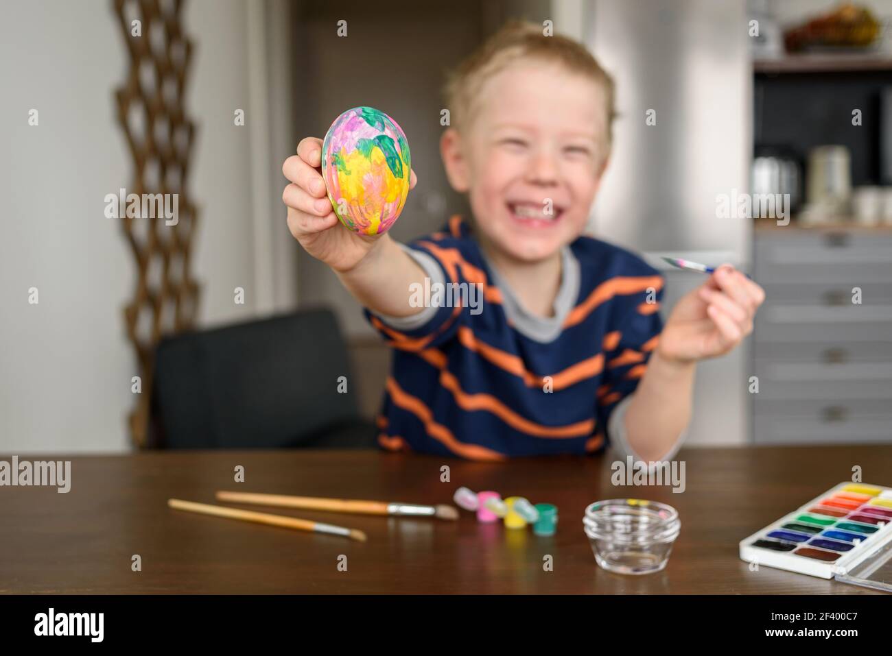 Happy Smiling Boy Färbung Osterei zu Hause mit Acrylfarbe. Kleiner Künstler, Hobby Stockfoto