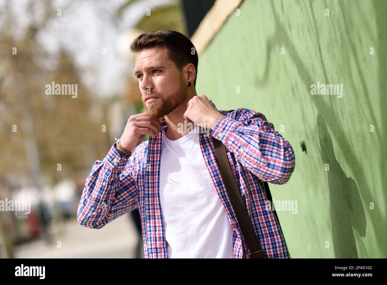 Attraktiver junger Mann, der im städtischen Hintergrund steht. Lifestyle-Kon. Attraktiver junger Mann, der im städtischen Hintergrund steht. Typ in legerer Kleidung. Lifestyle-Konzept. Stockfoto