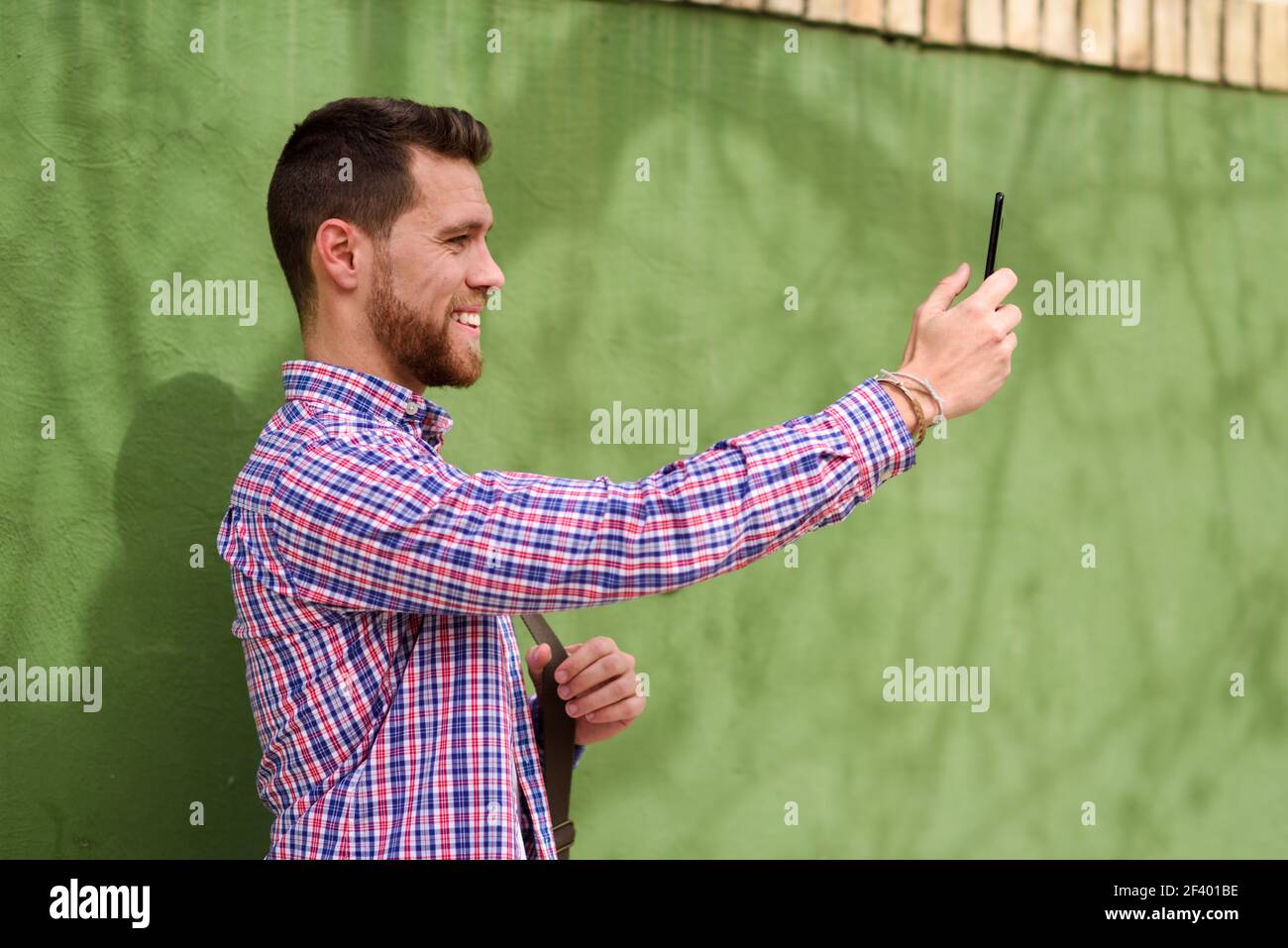 Junger Mann fotografiert mit seinem Smartphone im urbanen Backg. Junger Mann fotografiert mit seinem Smartphone im urbanen Hintergrund. Typ in legerer Kleidung. Lifestyle-Konzept. Stockfoto