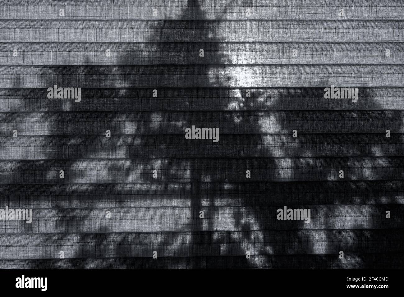 Ein gefalttes Fenster blind in der Morgensonne und der Schatten eines Baumes draußen. Stockfoto