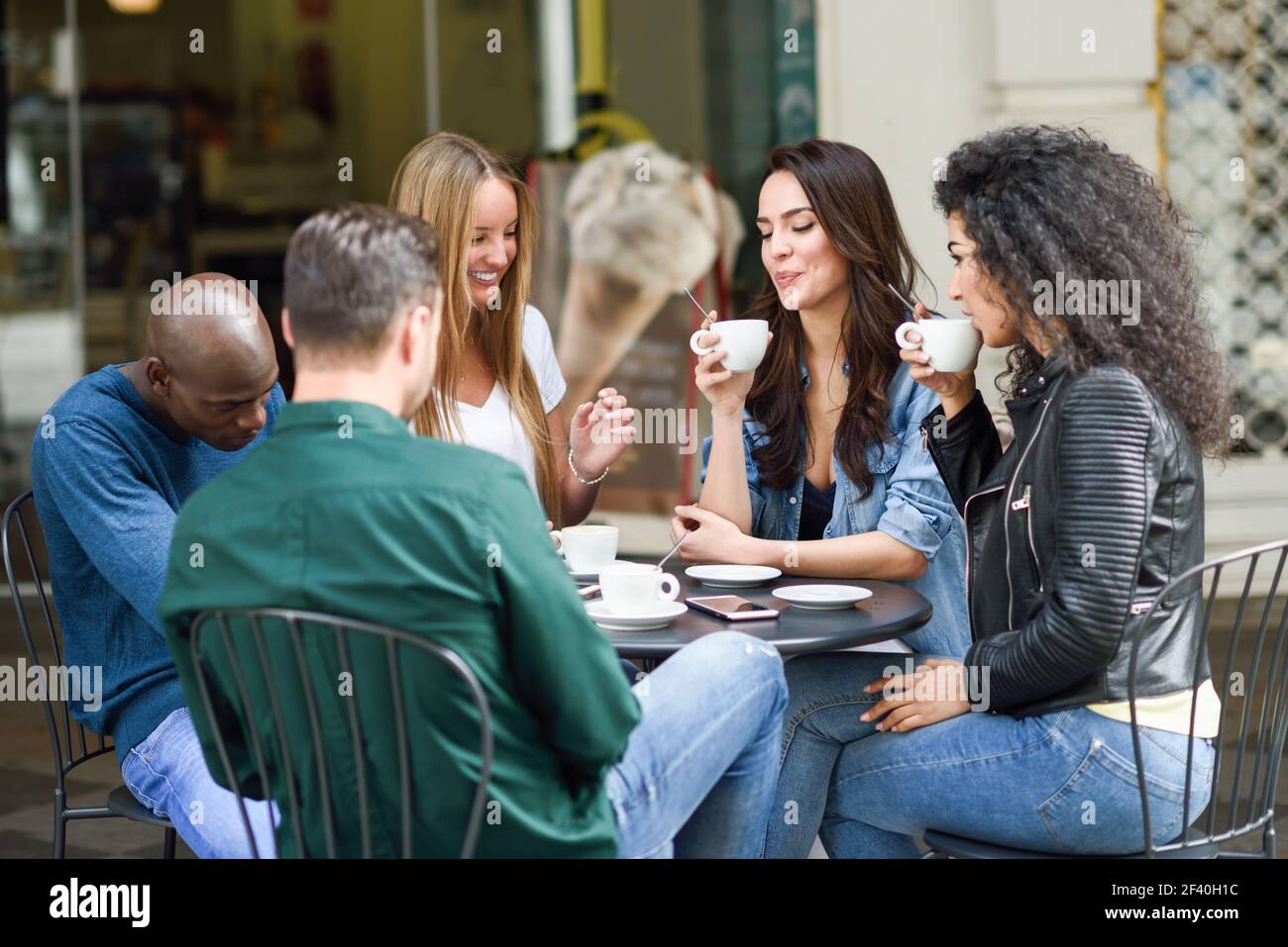 Multiethnische Gruppe von fünf Freunden einen Kaffee zusammen. Drei Frauen und zwei Männer im Cafe, reden, lachen und ihre Zeit genießen. Lifestyle und Freundschaft Konzepte mit realen Menschen Modelle Stockfoto
