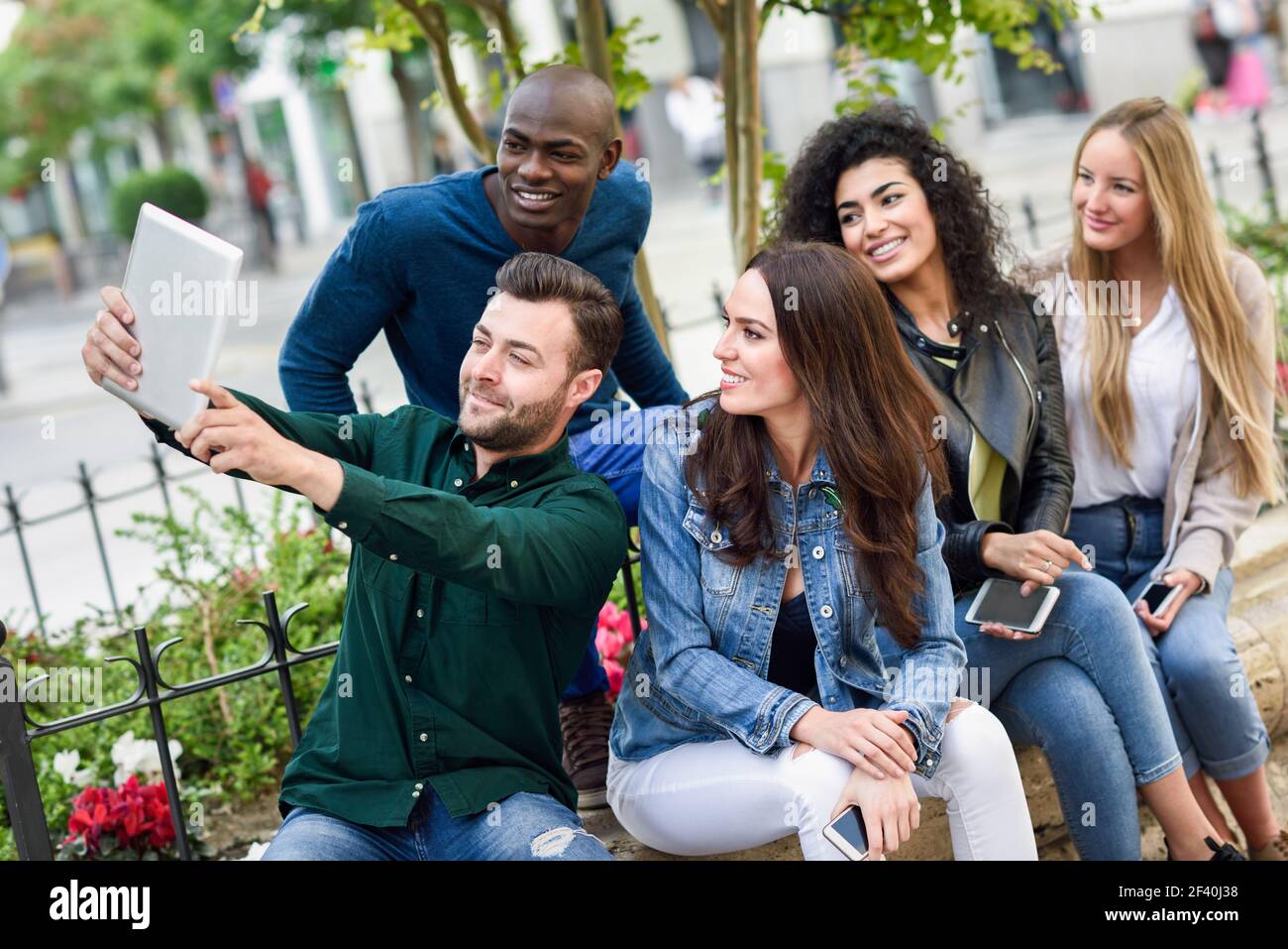 Multiethnische Gruppe junger Menschen, die gemeinsam im Freien Selfie fotografieren. Schöne lustige Frauen und Männer tragen lässige Kleidung im städtischen Hintergrund.. Multiethnische junge Menschen, die gemeinsam Selfie im urbanen Hintergrund machen Stockfoto