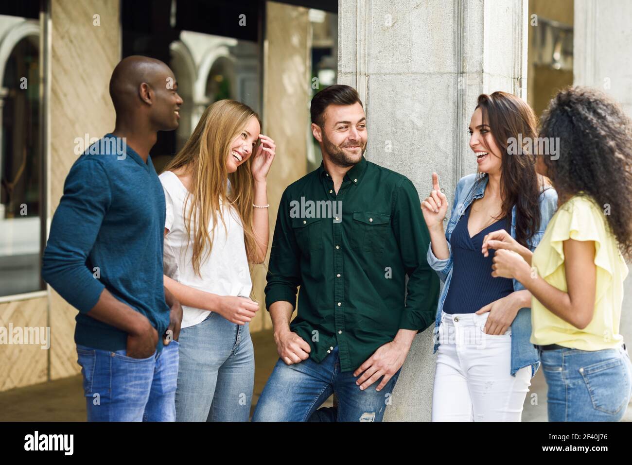 Multi-ethnische Gruppe von jungen Menschen Spaß zusammen im Freien im städtischen Hintergrund. Gruppe von schönen Frauen und Männer lachen zusammen. Multiethnische Gruppe von Freunden, die Spaß zusammen im städtischen Hintergrund haben Stockfoto