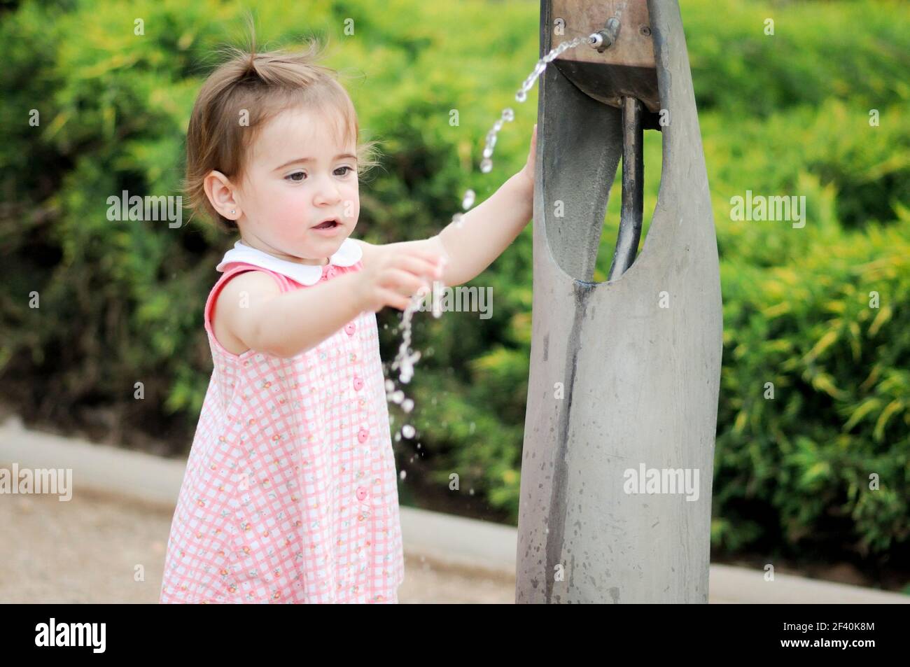 Liebenswert kleines Mädchen Trinkwasser in einem Park Brunnen. Kleines Mädchen trinkt Wasser in einem Park Brunnen Stockfoto