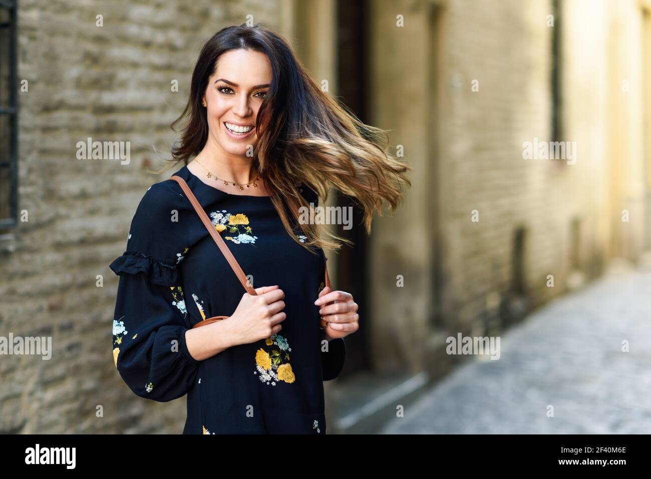 Junge Frau bewegt ihre langen Haare in städtischen Hintergrund. Frau in legerer Kleidung mit Pflege Frisur in Granada, Andalusien, Spanien.. Junge Frau bewegt ihre langen Haare in städtischen Hintergrund. Stockfoto