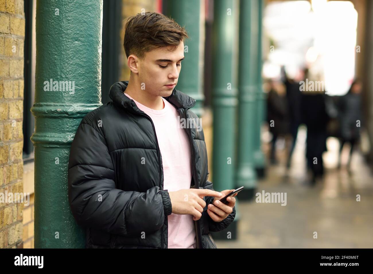 Junger Stadtmensch mit Smartphone im urbanen Hintergrund in London, Großbritannien. Junger Stadtmensch mit Smartphone im urbanen Hintergrund. Stockfoto