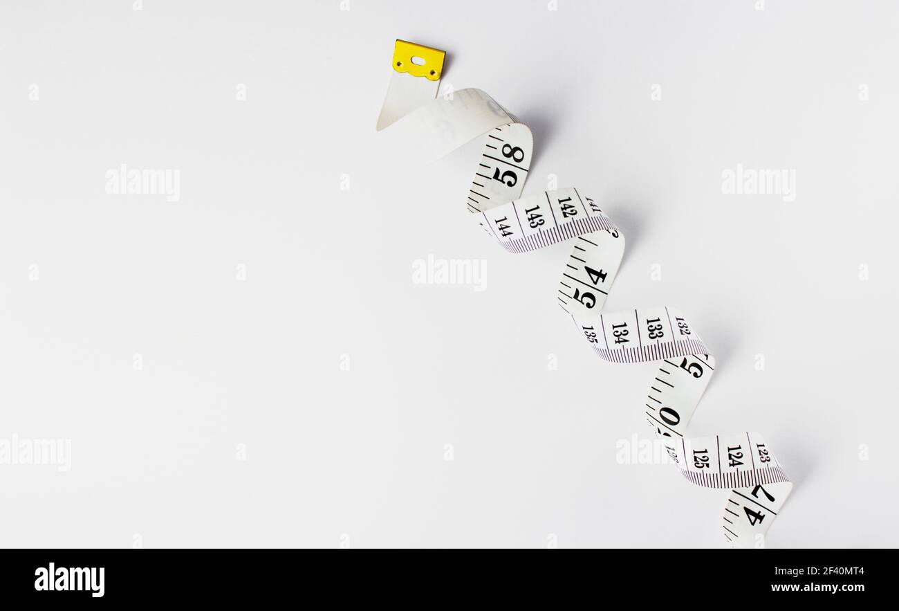 Weißes Maßband auf weißem Hintergrund, geringe Schärfentiefe. Schlankendes Maßband. Leerzeichen für Text. Stockfoto