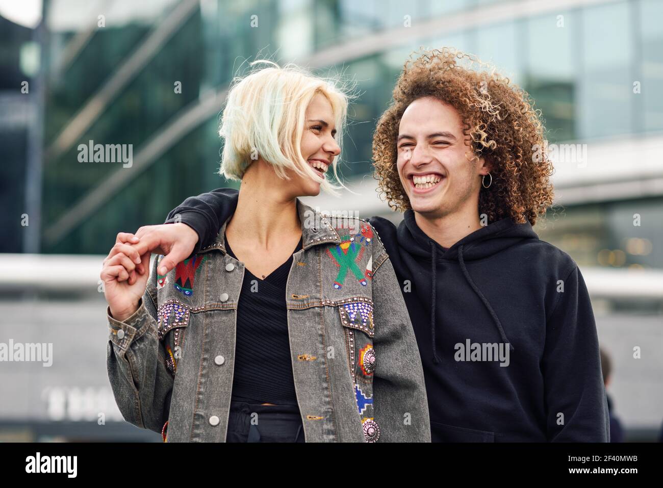 Glückliches Paar lachend im städtischen Hintergrund. Junge Frau und Mann genießen einander.. Glückliches junges Paar lachend im städtischen Hintergrund Stockfoto
