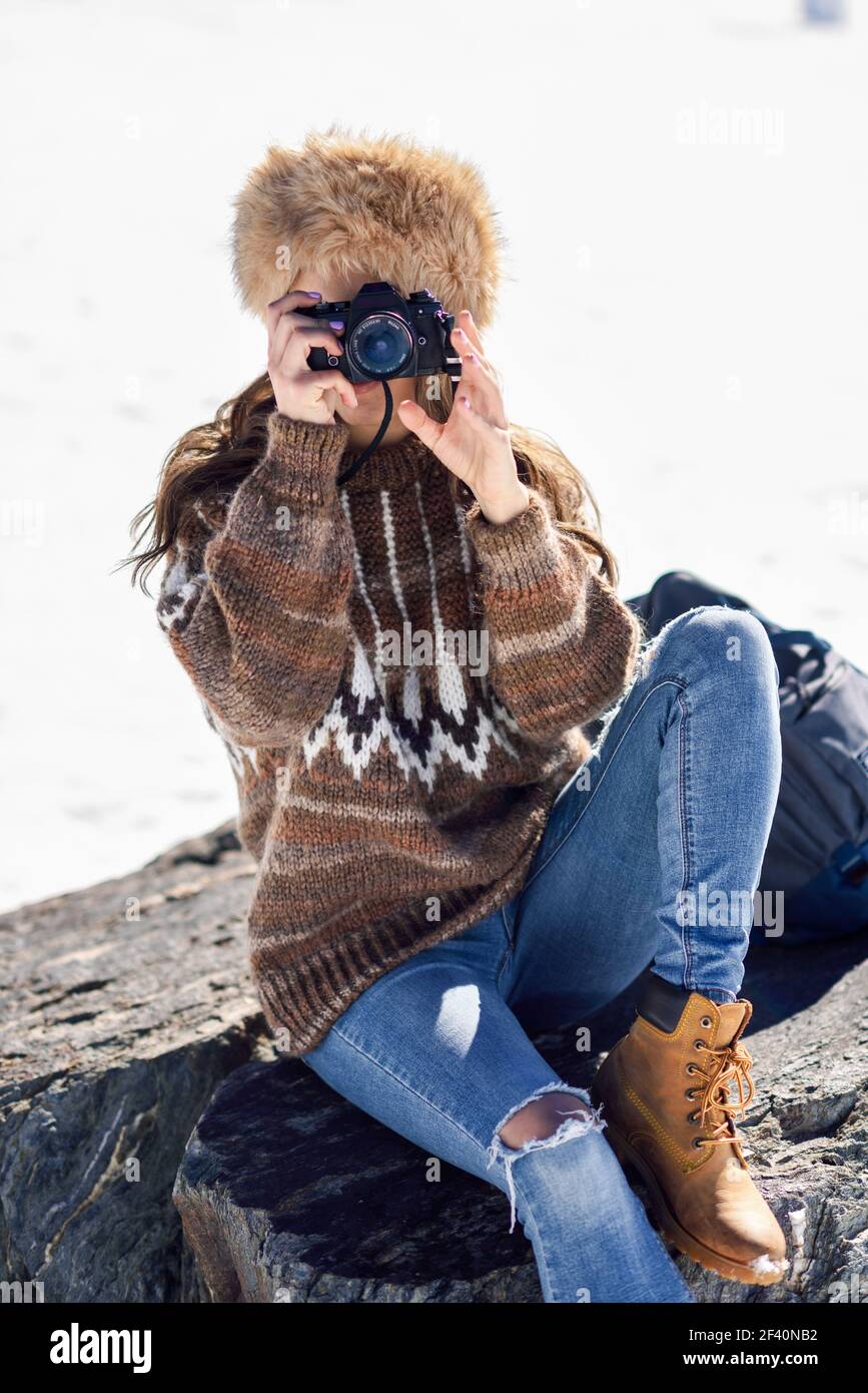 Junge Frau, die im Winter in den verschneiten Bergen fotografiert, in der Sierra Nevada, Granada, Spanien. Frau trägt Winterkleidung. Junge Frau fotografiert in den verschneiten Bergen Stockfoto