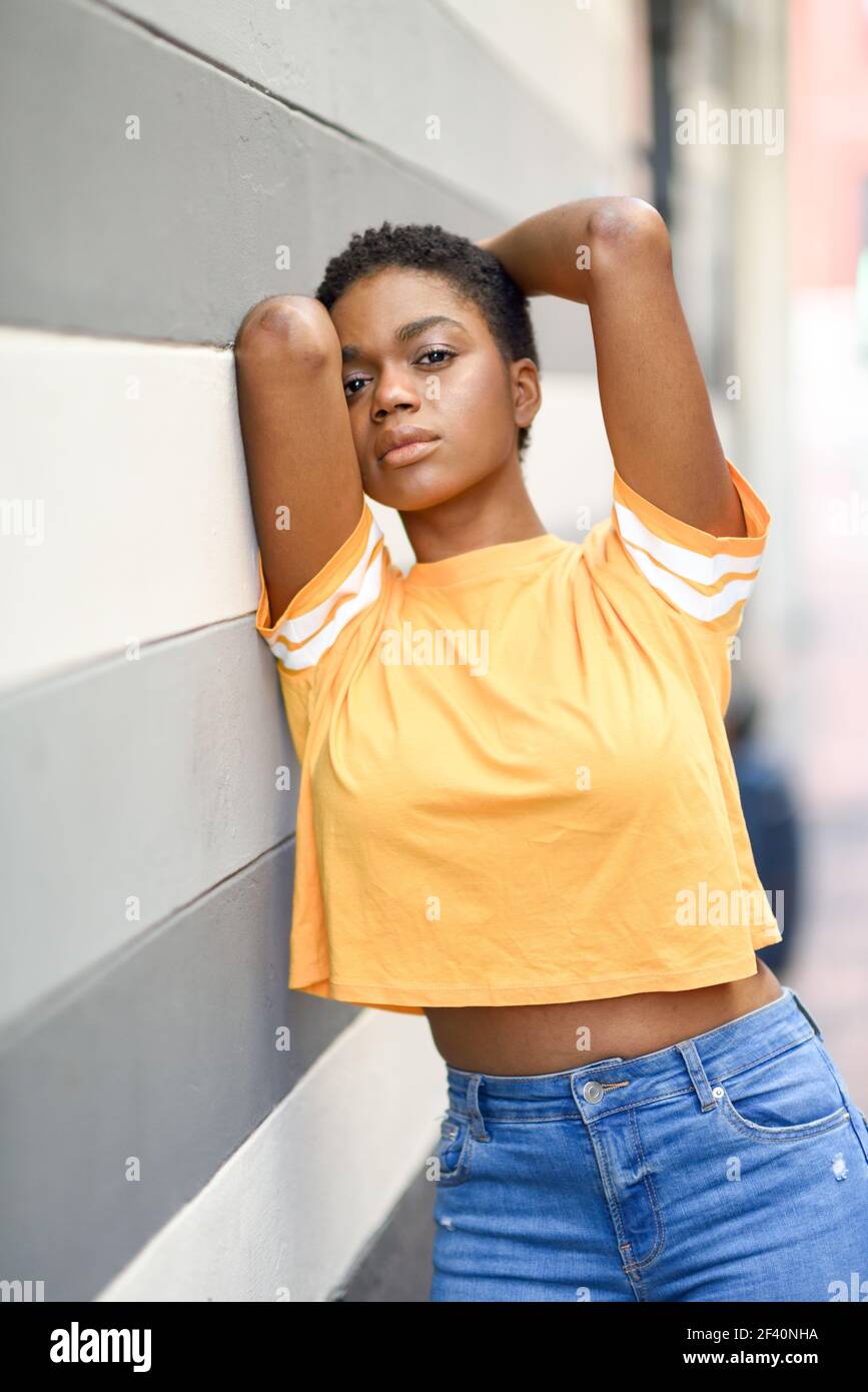 Nachdenkliche schwarze Frau mit traurigem Ausdruck auf Stadtmauer. Nachdenkliche schwarze Frau mit traurigem Ausdruck im Freien. Stockfoto