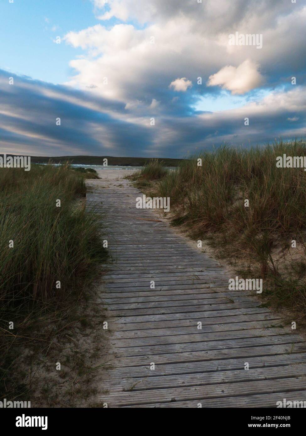 Holzweg durch Dünen zum Meer ein wolkig Himmel In irland Stockfoto