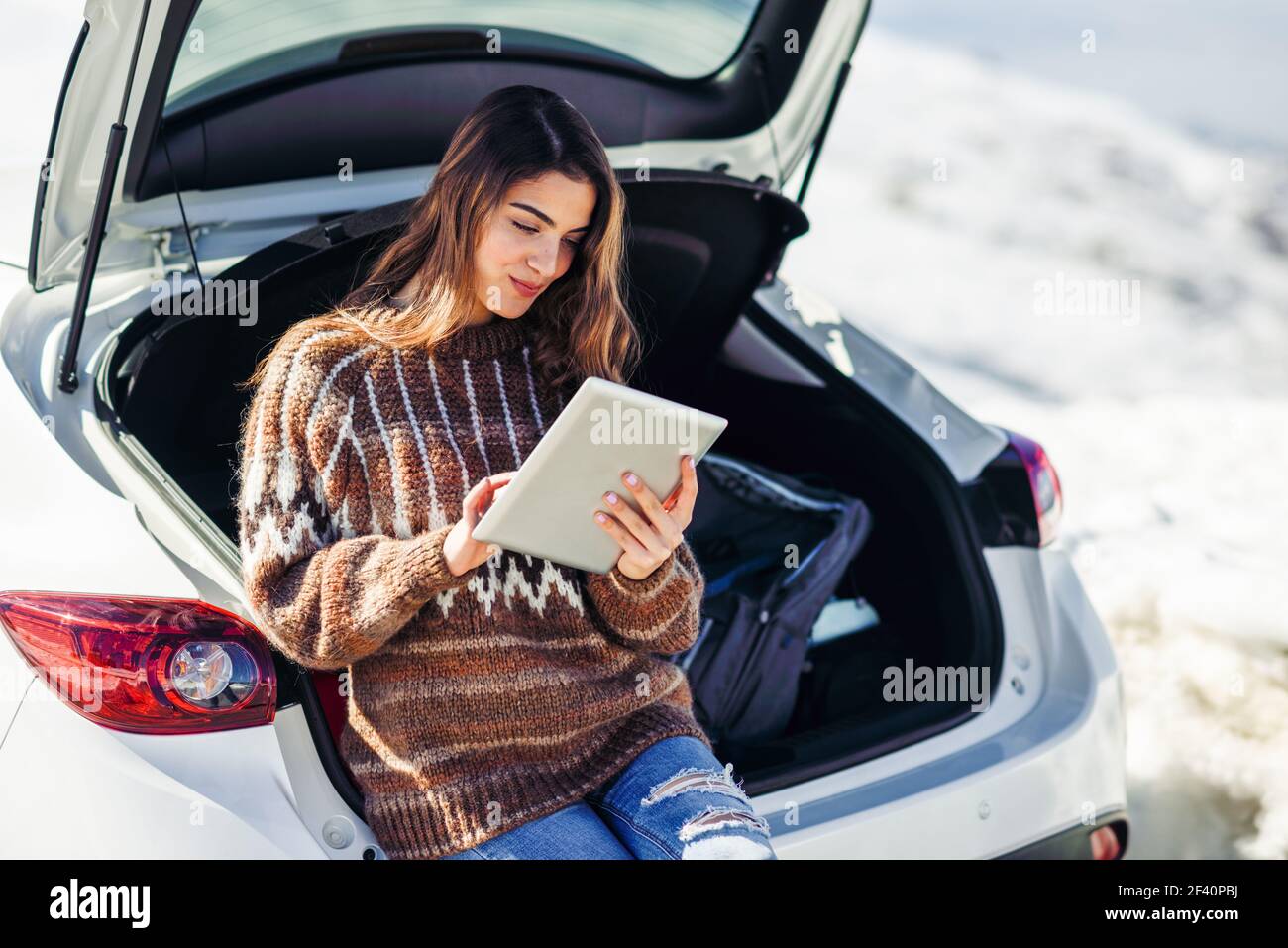 Junge Reisende Frau mit digitalen Computer in verschneiten Bergen im Winter, in Sierra Nevada, Granada, Spanien. Frau trägt Winterkleidung. Junge Reisende Frau mit digitalen Computer in verschneiten Bergen im Winter. Stockfoto