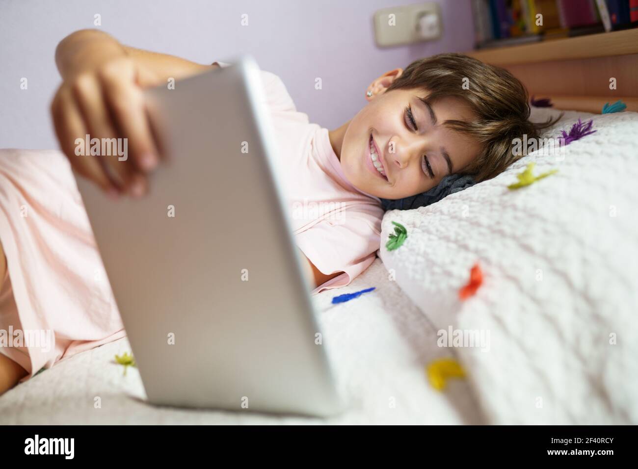 Nettes Mädchen, acht Jahre alt, mit einem Tablet-Computer in ihrem Schlafzimmer. Mädchen mit kurzen Haaren.. Nettes Mädchen mit einem Tablet-Computer in ihrem Schlafzimmer Stockfoto