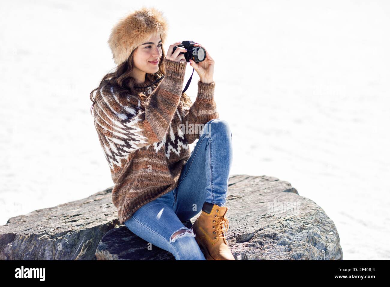 Junge Frau, die im Winter in den verschneiten Bergen fotografiert, in der Sierra Nevada, Granada, Spanien. Frau trägt Winterkleidung. Junge Frau fotografiert in den verschneiten Bergen Stockfoto