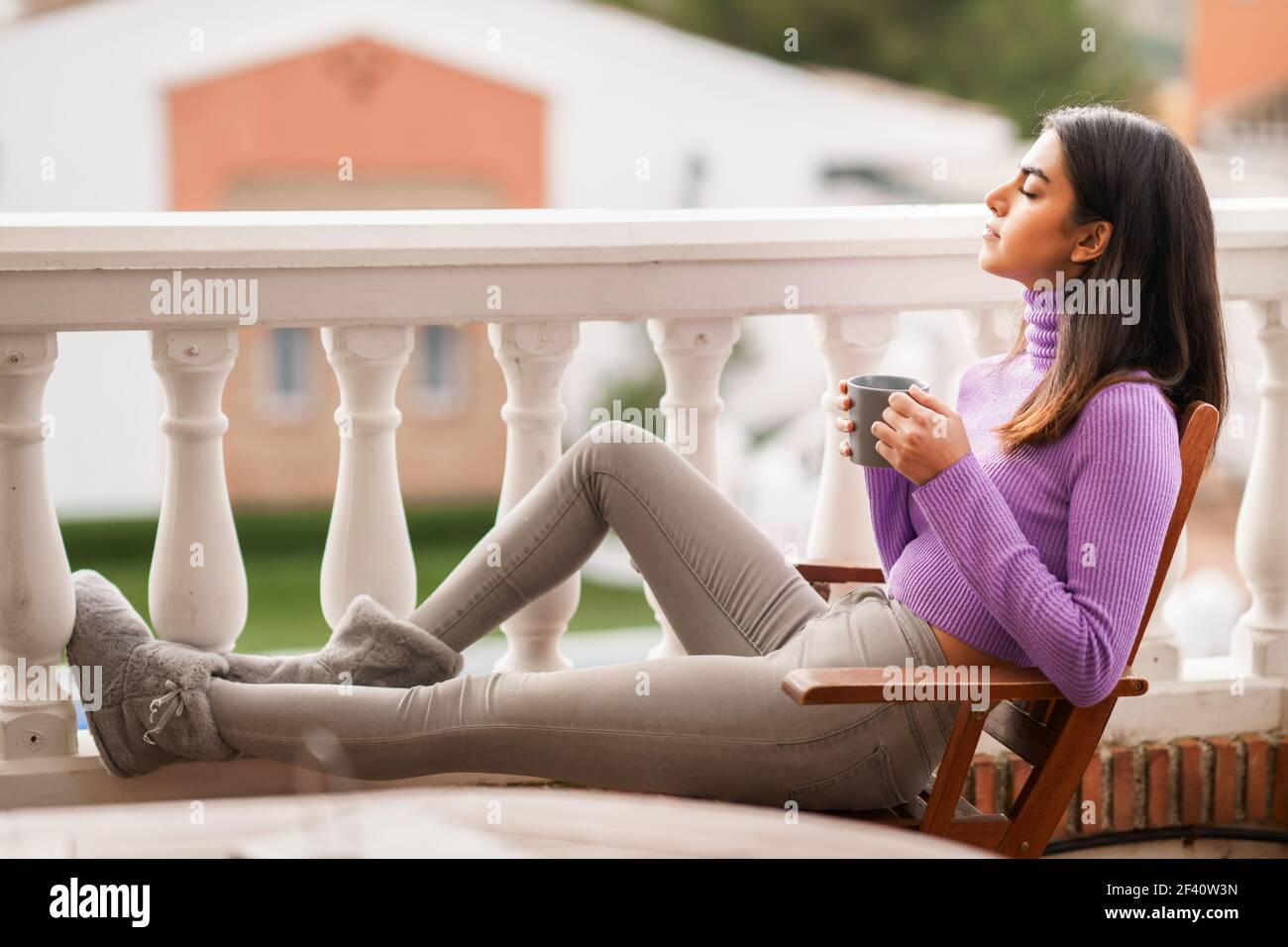 Perserin sitzt in einem Sessel auf ihrem Balkon mit einer Tasse Kaffee. Perserin auf ihrem Balkon mit einer Tasse Kaffee Stockfoto