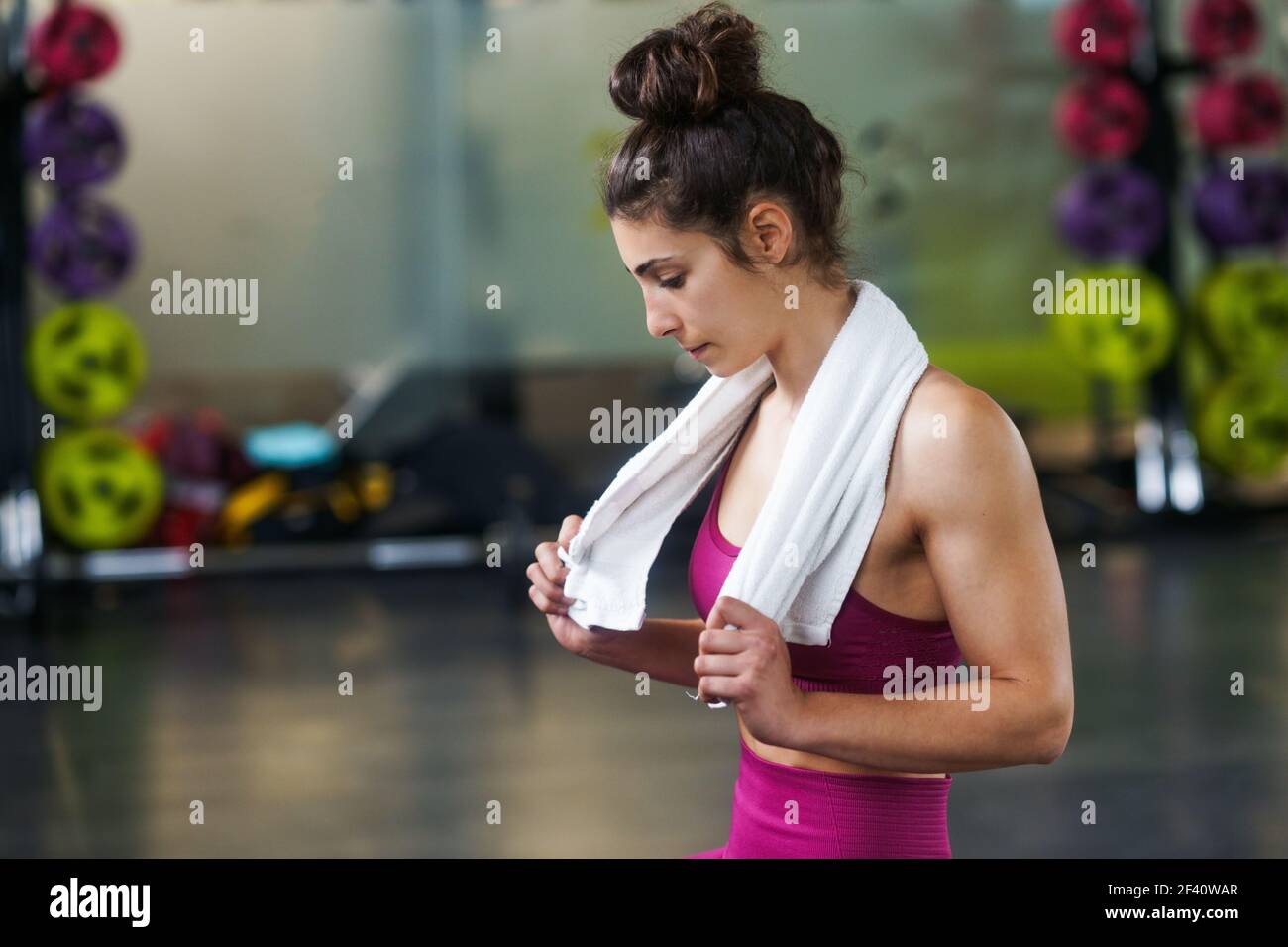 Frau ruht sich nach Übungen im Fitnessstudio mit einem weißen Handtuch aus. Frau ruht sich nach den Übungen im Fitnessstudio aus Stockfoto