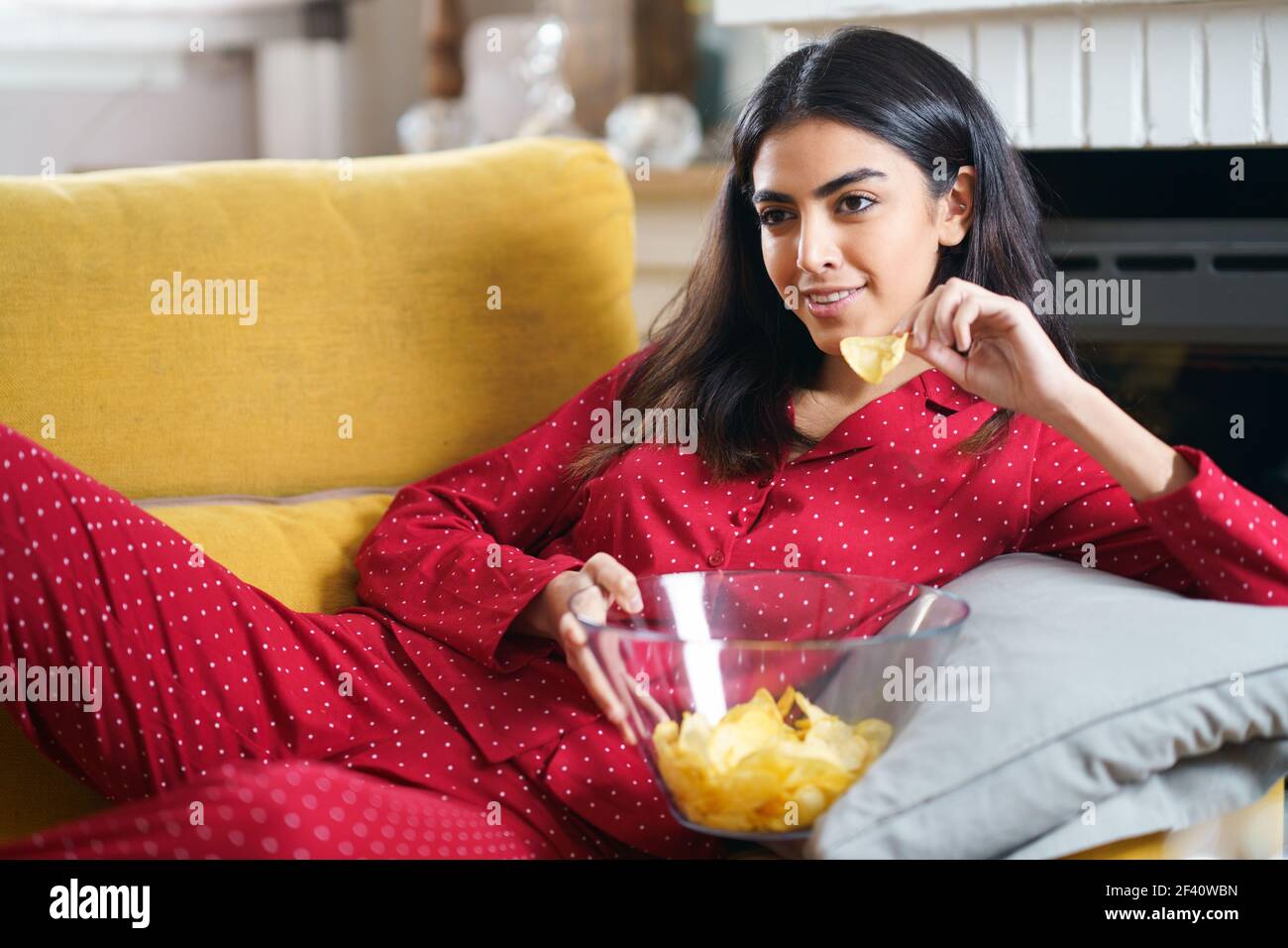 Perserin zu Hause beim Fernsehen. Mädchen essen Chips Kartoffeln. Perserin zu Hause Fernsehen Chips essen Kartoffeln Stockfoto