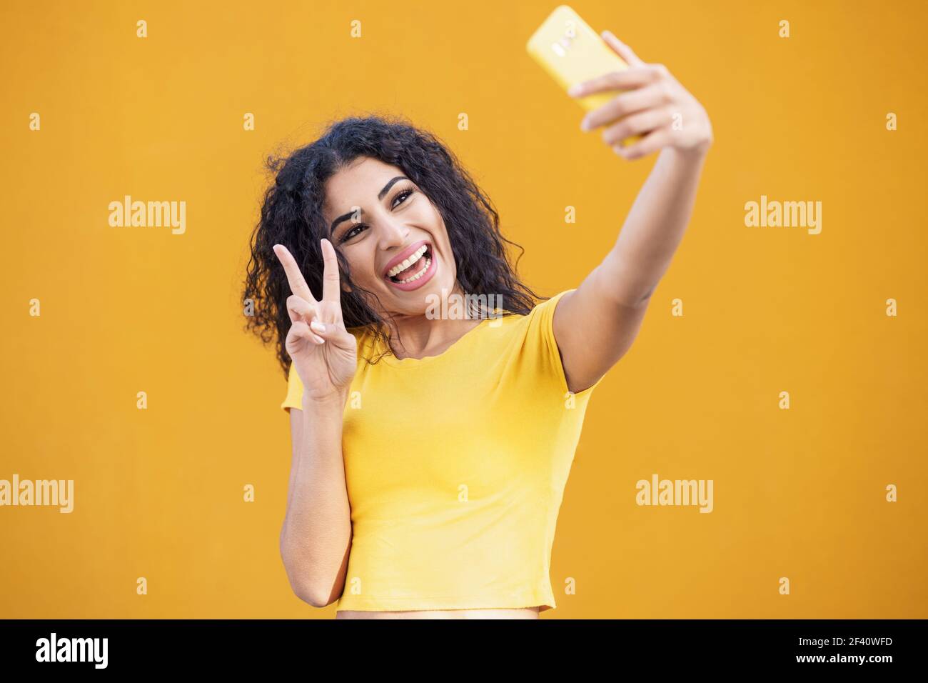 Lustige arabische Frau macht Selfie-Foto mit Smartphone. Lockiges Haar weiblich.. Junge arabische Frau, die Selfie-Fotografie mit dem Smartphone. Stockfoto