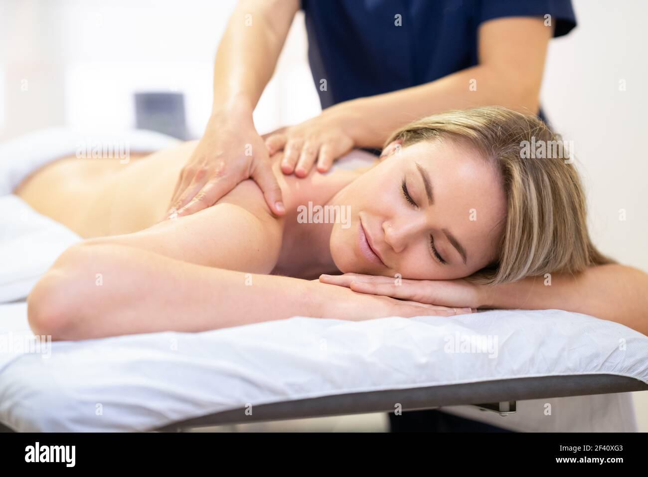 Junge Frau, die auf einer Bahre liegt und eine Rückenmassage in einem Spa-Zentrum erhält. Frau liegt auf einer Bahre und erhält eine Rückenmassage. Stockfoto